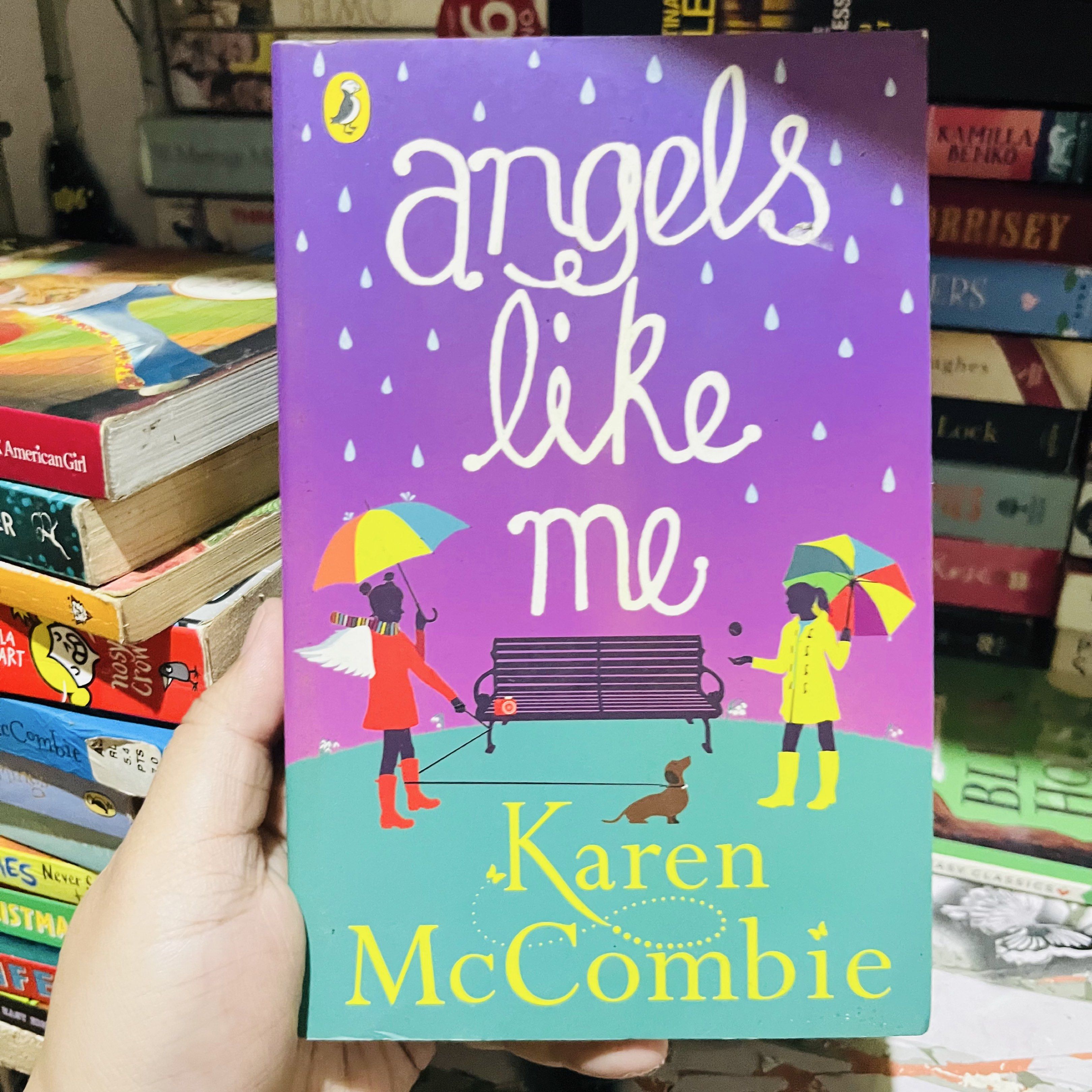 Angels Like Me by Karen McCombie (Category: Storybooks) located in Taguig. Submitted by hazebooksdeclutter (Listing ID 1419827196, Image 1). Description: - Title: Angels Like Me - Author: Karen McCombie - Publisher: Penguin - Cover: Purple background with illustrations of people, umbrellas, and a dog. - Author's name in green font..