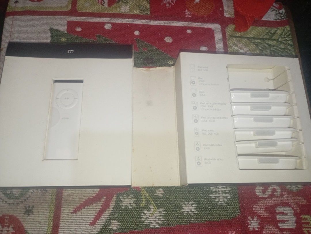 Apple iPod Remote with 6 Different iPod unit adapter (Category: Portable Music Players) located in Pasig City. Submitted by live_cosmicstorm (Listing ID 1419866274, Image 3). Description: Includes the Apple iPod remote, dock, and six white accessories. The remote is white and has a circular control pad. The accessories are in individual white cases. The original box is included, which is black with the Apple logo. The box also contains a white in