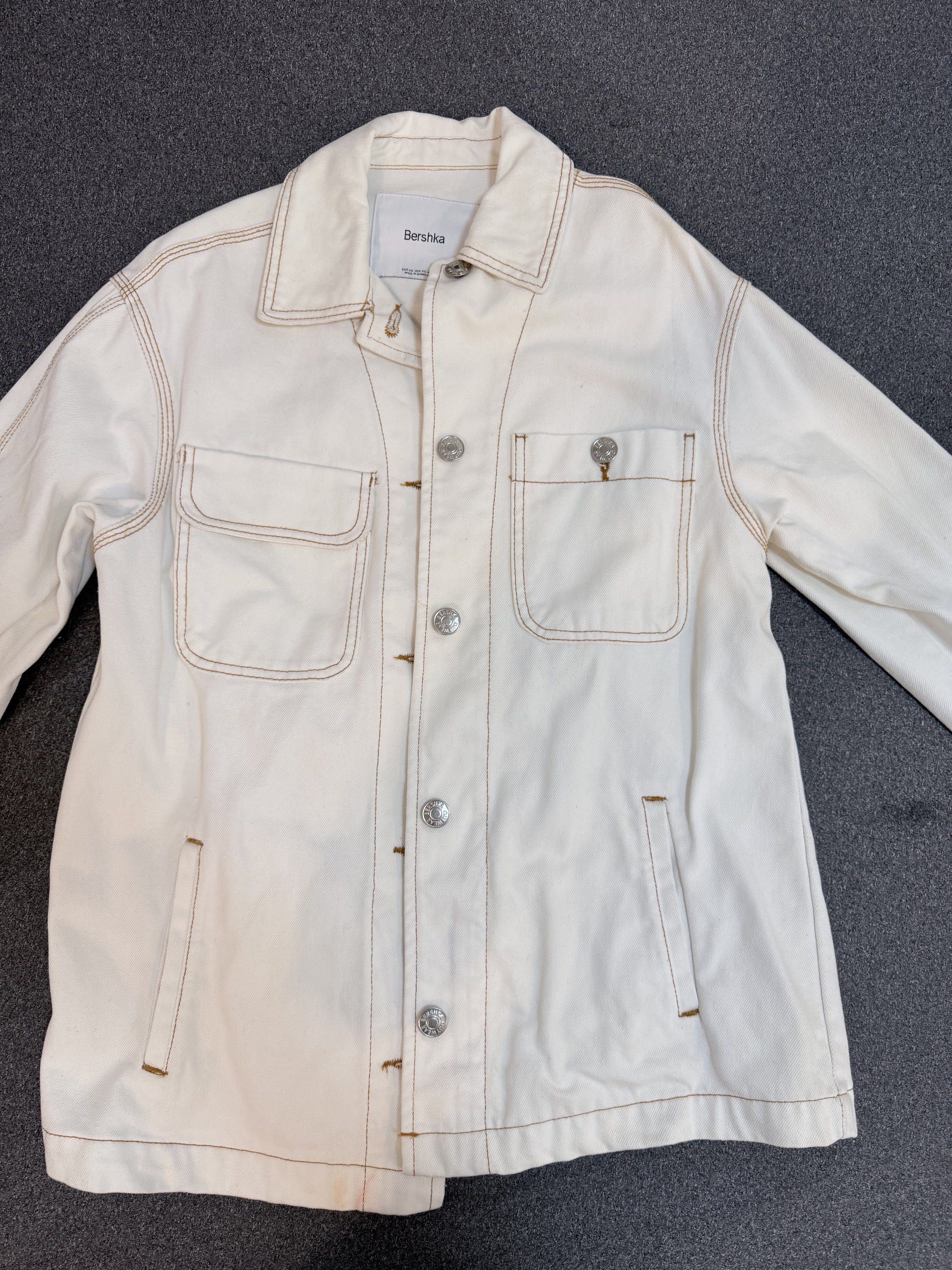 Bershka White Denim Jacket (Category: Coats, Jackets and Outerwear) located in Valenzuela. Submitted by kimerunn (Listing ID 1419852713, Image 1). Description: White denim jacket from Bershka. Features a button-down closure, two chest pockets, and two side pockets. The jacket has contrasting stitching and a classic collar..