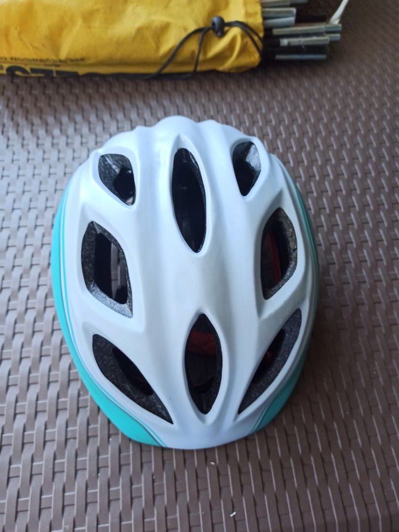 Bike Helmet - White and Teal size Medium (Category: Bicycles) located in Caloocan City. Submitted by rtarellano (Listing ID 1419911667, Image 1). Description: Bike helmet features a white and teal color scheme. It has multiple vents for airflow and adjustable straps for a secure fit. The interior includes padding for comfort and protection. The helmet has a dial adjustment system at the back for a customized fit. The straps are black with red pad