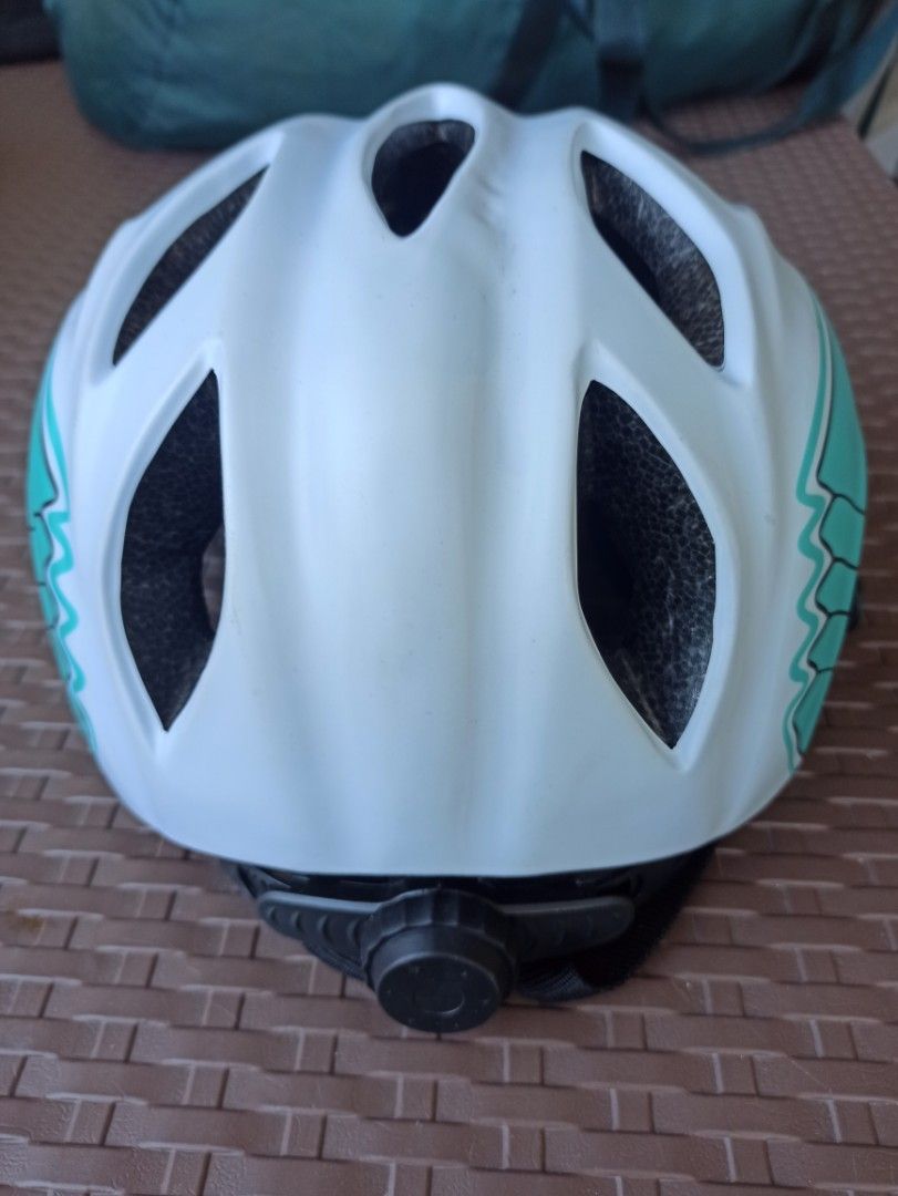 Bike Helmet - White and Teal size Medium (Category: Bicycles) located in Caloocan City. Submitted by rtarellano (Listing ID 1419911667, Image 3). Description: Bike helmet features a white and teal color scheme. It has multiple vents for airflow and adjustable straps for a secure fit. The interior includes padding for comfort and protection. The helmet has a dial adjustment system at the back for a customized fit. The straps are black with red pad