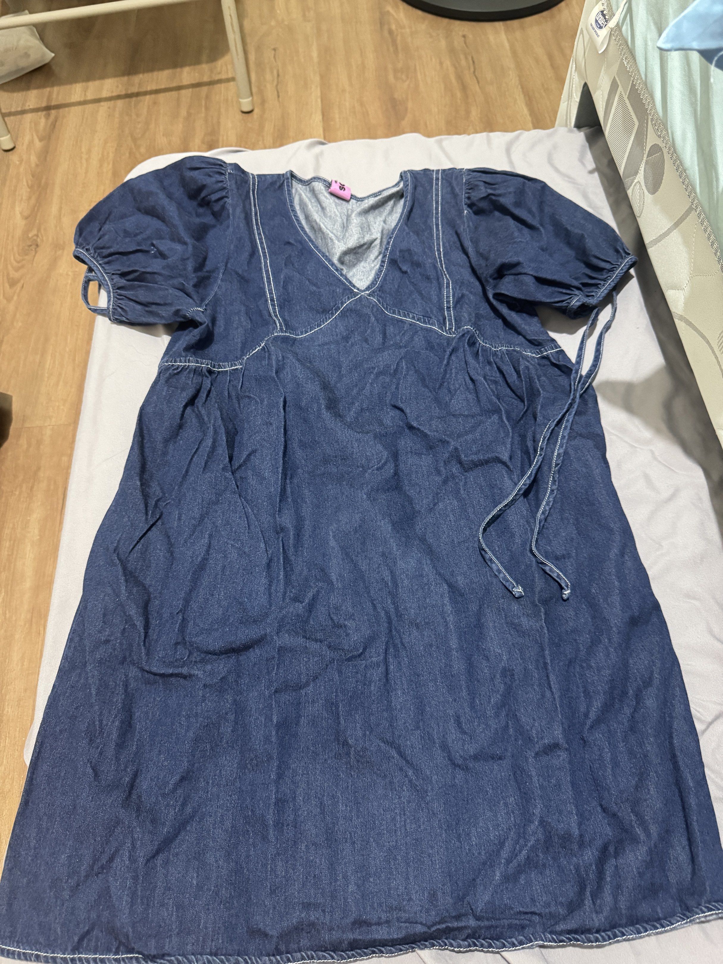 Denim Dress with Puff Sleeves (Category: Dresses) located in Pasig City. Submitted by caaex (Listing ID 1419940649, Image 1). Description: Denim dress features a V-neckline and puff sleeves. It has white stitching details and tie-up strings on the sleeves. The brand tag is visible in the image. The dress has a relaxed fit..