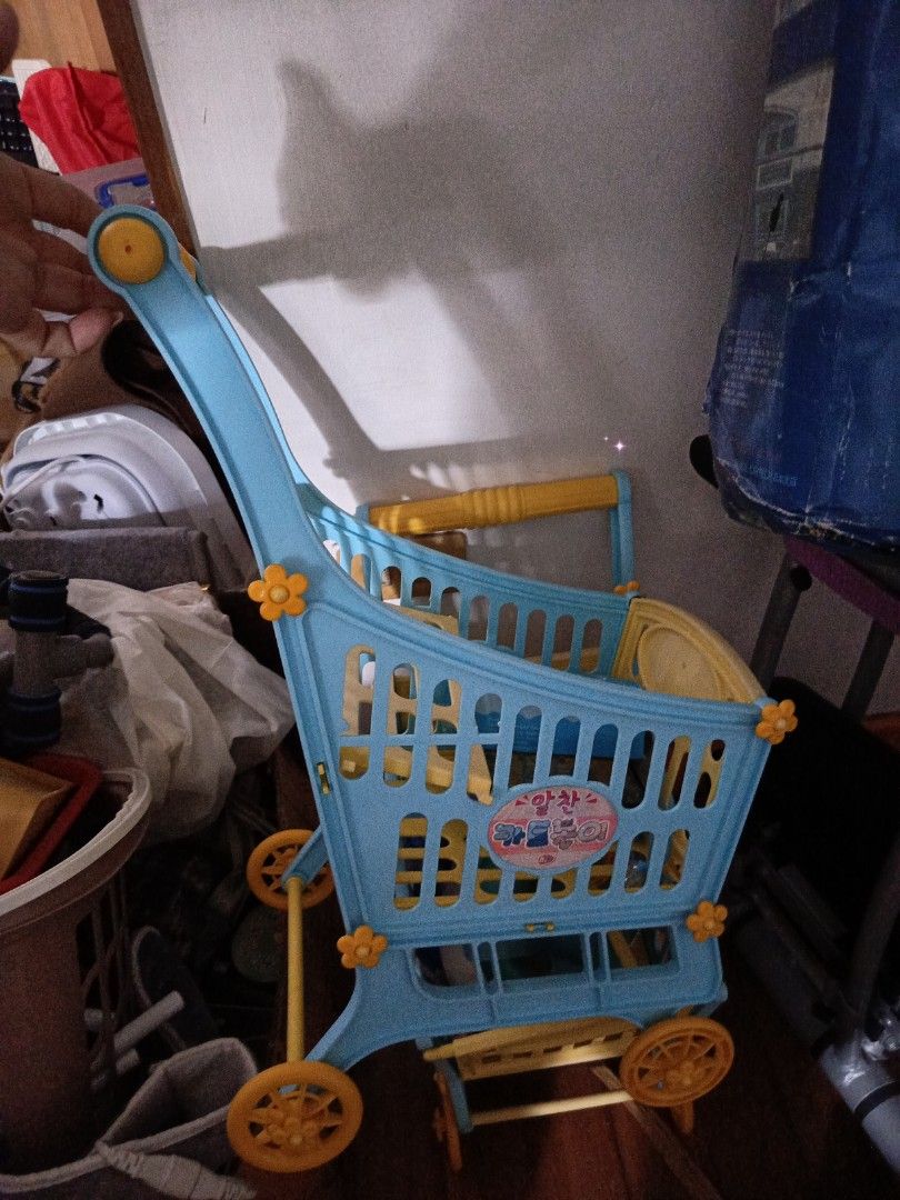 Kids' Toy Shopping Cart (Category: Toys & Games) located in Manila. Submitted by christcels78475 (Listing ID 1419812196, Image 2). Description: - Blue and yellow toy shopping cart for kids - Features multiple levels for storage - Easy to push with a handle - Includes wheels for mobility - Made of durable plastic - Decorative design on the front - Ideal for imaginative play.