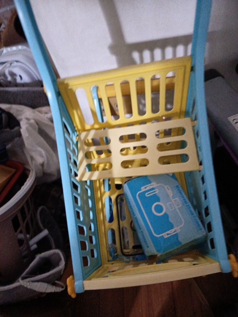 Kids' Toy Shopping Cart (Category: Toys & Games) located in Manila. Submitted by christcels78475 (Listing ID 1419812196, Image 3). Description: - Blue and yellow toy shopping cart for kids - Features multiple levels for storage - Easy to push with a handle - Includes wheels for mobility - Made of durable plastic - Decorative design on the front - Ideal for imaginative play.