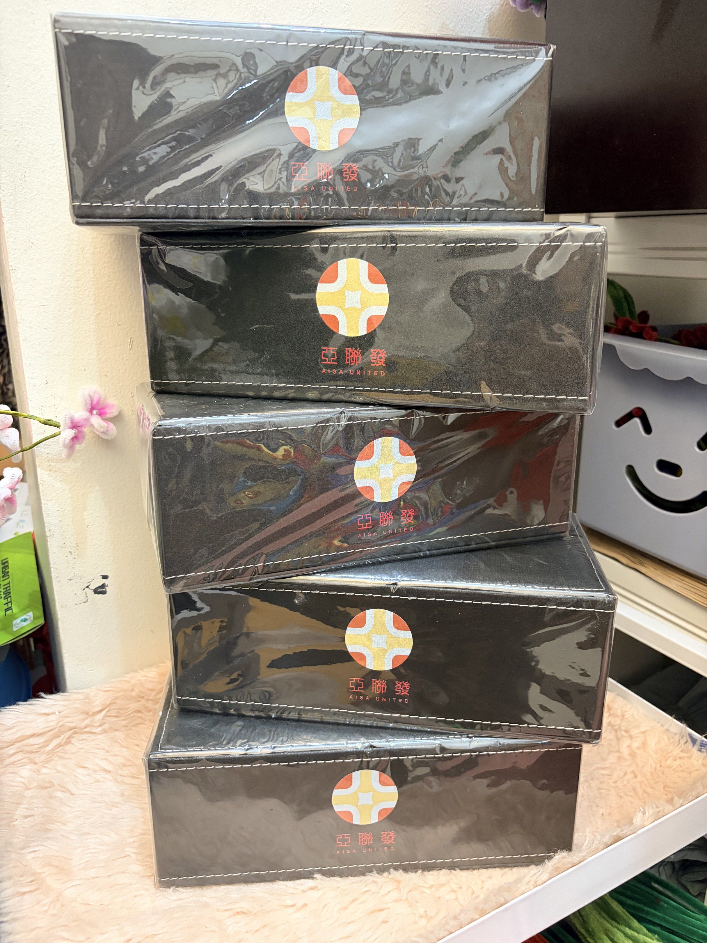 Leather Tissue Box with Logo (Category: Storage Boxes & Baskets) located in Mandaluyong City. Submitted by home_box.ae (Listing ID 1419822898, Image 2). Description: - Black rectangular tissue box - Features a stitched border - Includes a circular logo with a cross design - Made of a leather-like material - Multiple boxes available - Brand new, still in original packaging.