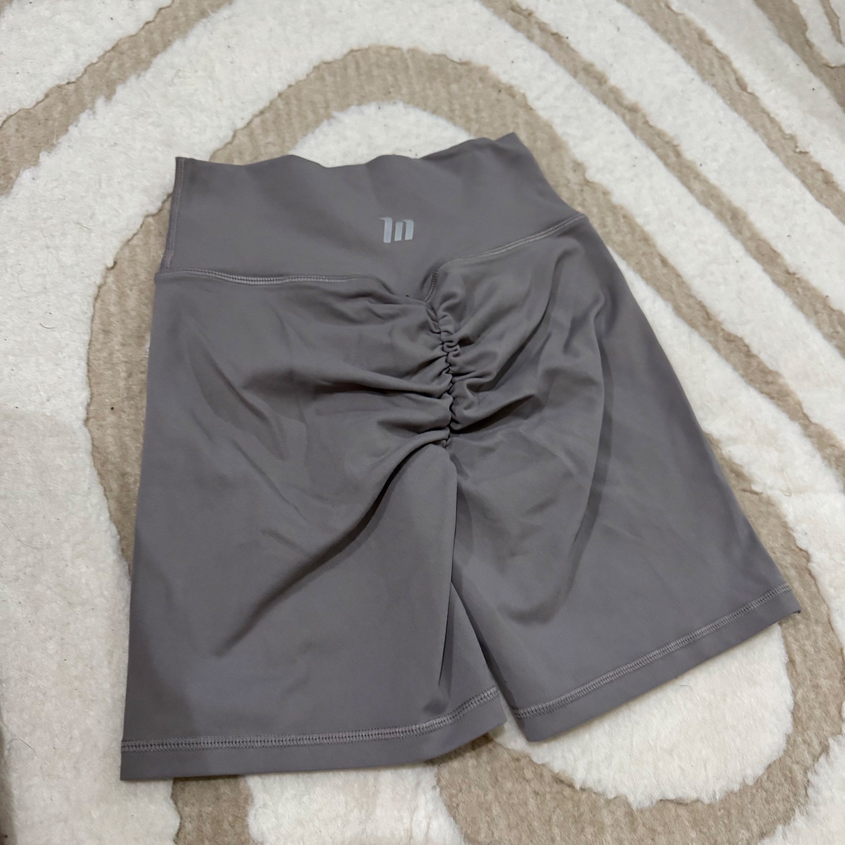 Muscle nation Scrunch Butt Shorts (Category: Activewear) located in Makati City. Submitted by finders.keep.hers (Listing ID 1419849844, Image 2). Description: - Gray high-waisted shorts - Scrunch butt design - "IN" logo on back waistband - Made of smooth, stretchy material - Ideal for workouts and casual wear.