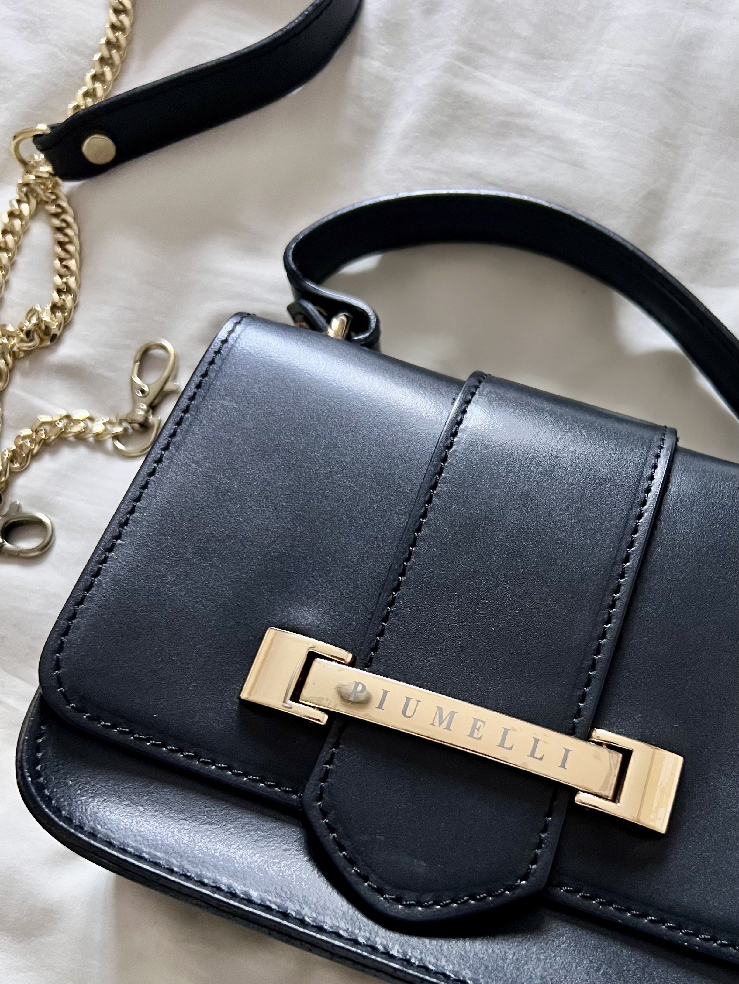 Piumelli Milano Black Leather Handbag (Category: Luxury Bags & Wallets) located in Rizal. Submitted by livebird-217e (Listing ID 1419859851, Image 2). Description: Price FIXED for this one, thank you. - Authentic Piumelli ITALY leather handbag - Gold-tone metal bar detail - Detachable gold chain strap and top handle - Luxurious suede lining - Includes a small interior pocket - Made in Italy - Comes with a dust bag Size/ 6”x 5” İn like new used co