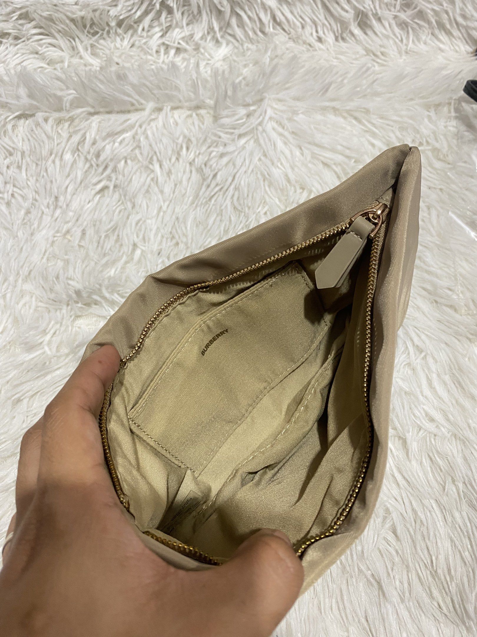 Burberry Beige Clutch (Category: Luxury Bags & Wallets) located in Manila. Submitted by motscollections041421 (Listing ID 1420016231, Image 3). Description: - Authentic Burberry clutch - Color: Beige - Closure: Zipper - Interior: Small pocket and Burberry logo lining - Materials: 100% polyester (body and trim), 90% polyester/10% cotton (lining) - Made in China.
