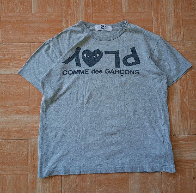 Comme des Garcons Play Grey T-shirt (Category: Tshirts & Polo Shirts ) located in Boston. Submitted by johnpaulvi30029 (Listing ID 1420013811, Image 1). Description: - Grey Comme des Garcons Play T-shirt - Features the iconic heart logo with eyes - Brand name printed on the front - Crew neck and short sleeves - Soft, comfortable fabric - Standard fit.