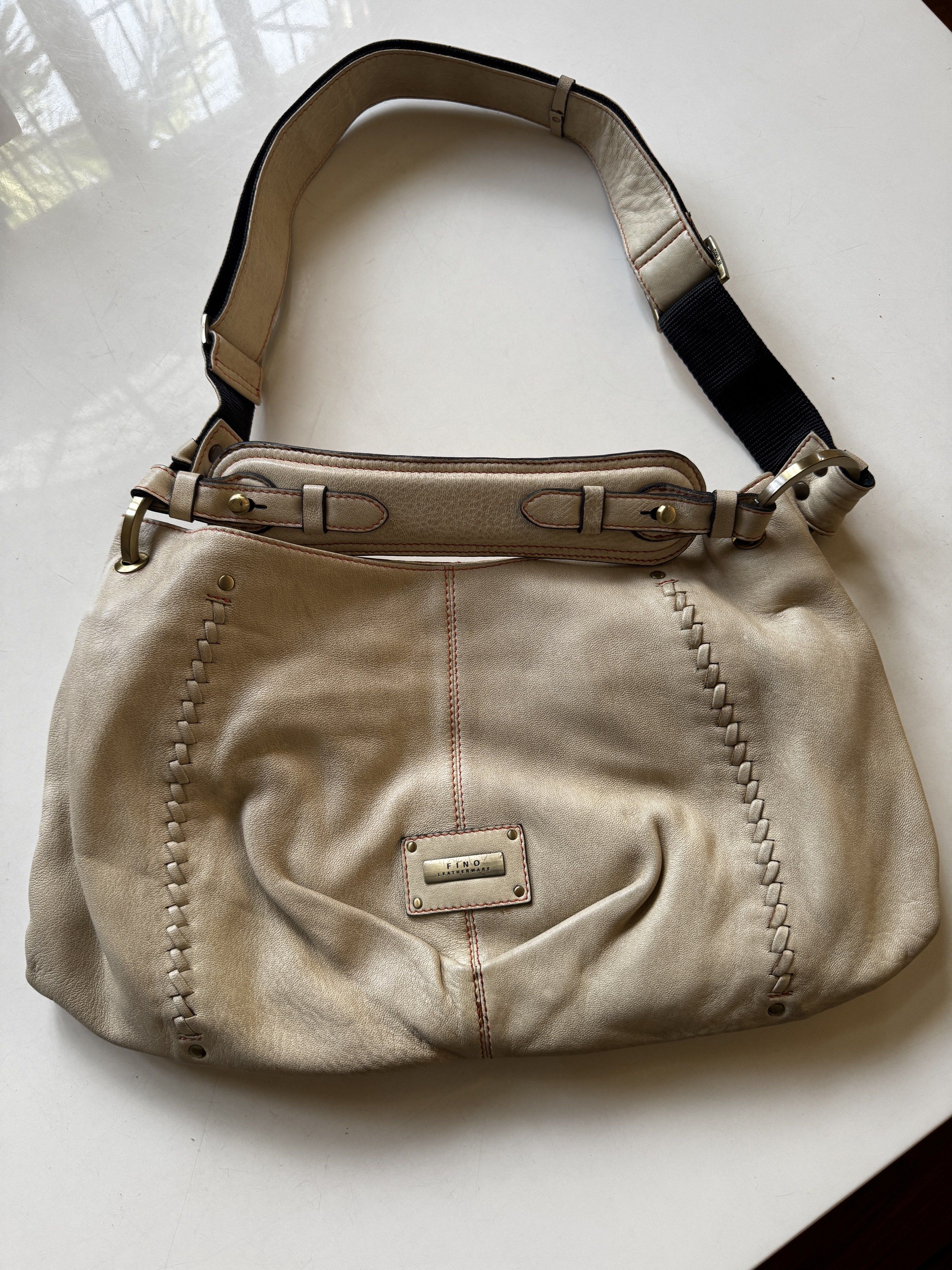 Fino Leatherware Shoulder Bag (Category: Luxury Bags & Wallets) located in Quezon City. Submitted by tulip03 (Listing ID 1420040228, Image 1). Description: - Cream-colored shoulder bag - Brand: Fino Leatherware - Design: Stitched sides with red stitch detail - Interior: Orange with zipper closure - Features: Adjustable shoulder strap - Details: Rectangular Fino Leatherware label on the front.