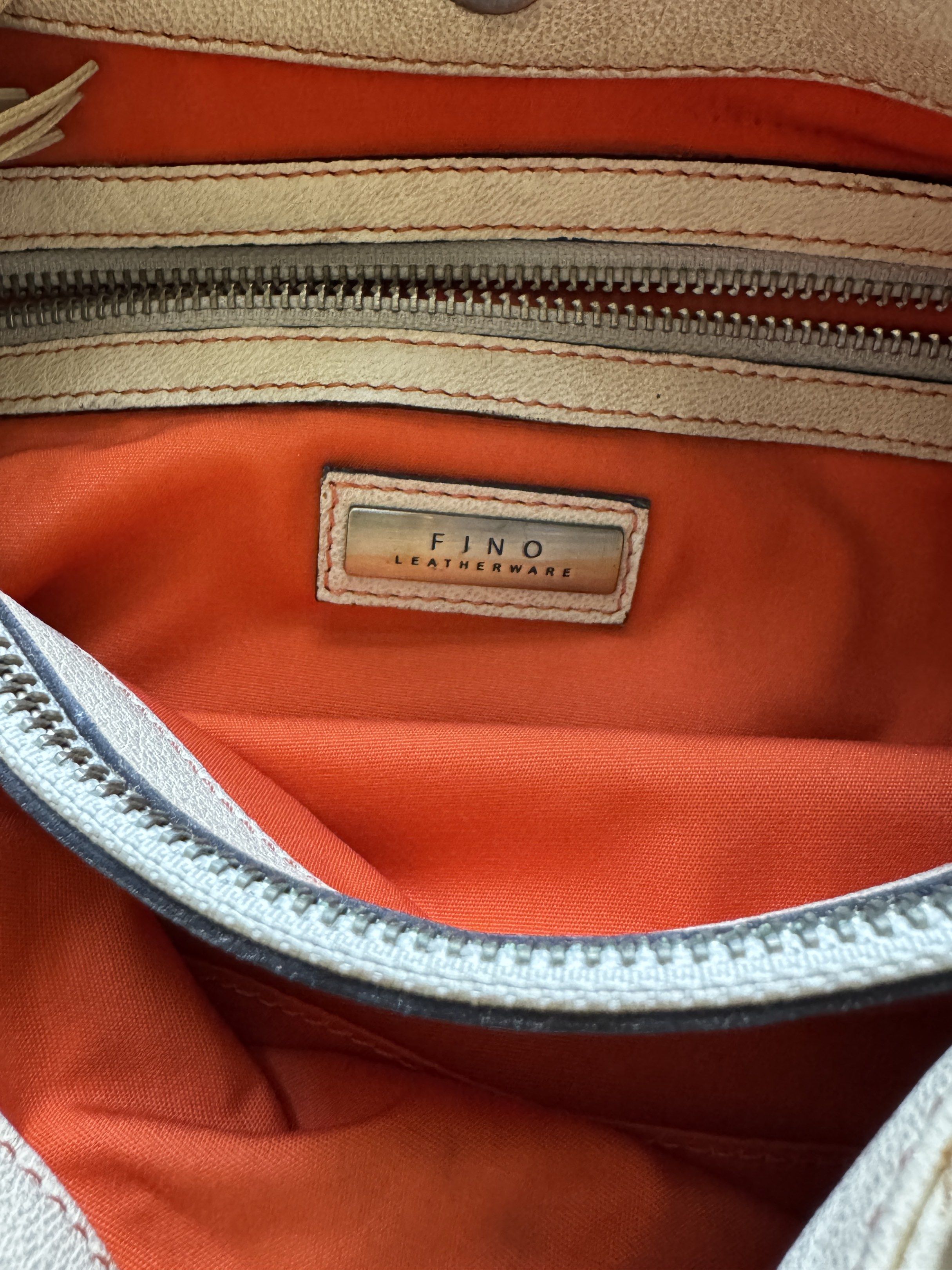 Fino Leatherware Shoulder Bag (Category: Luxury Bags & Wallets) located in Quezon City. Submitted by tulip03 (Listing ID 1420040228, Image 3). Description: - Cream-colored shoulder bag - Brand: Fino Leatherware - Design: Stitched sides with red stitch detail - Interior: Orange with zipper closure - Features: Adjustable shoulder strap - Details: Rectangular Fino Leatherware label on the front.