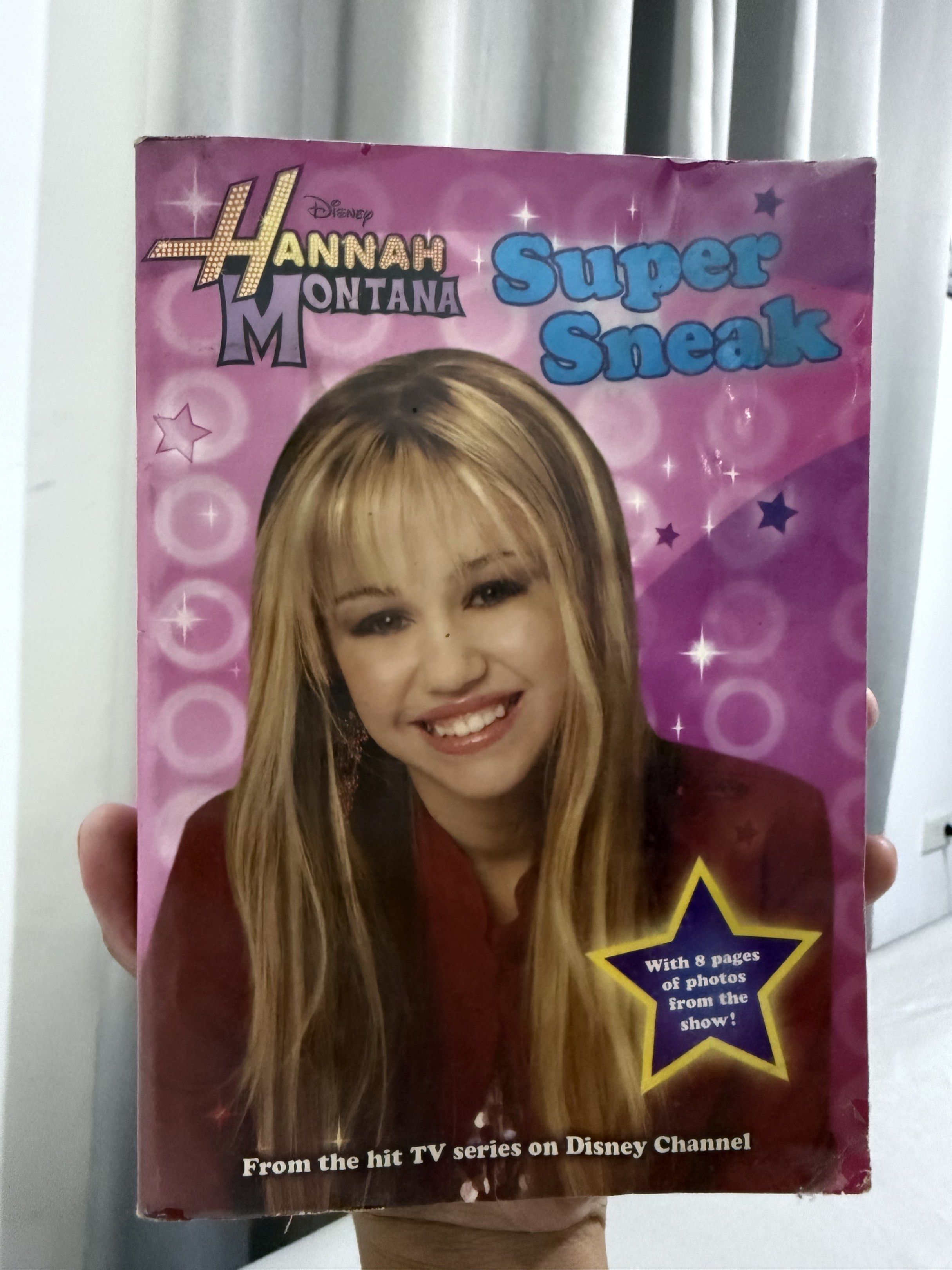 Hannah Montana Super Sneak Book (Category: Children's Books) located in Mansalay. Submitted by declutterandco (Listing ID 1420086428, Image 1). Description: - Hannah Montana "Super Sneak" book. - Features photos from the Disney Channel show. - 8 pages of photos. - Cover: Hannah Montana with a purple background and stars. - Title: "Super Sneak"..
