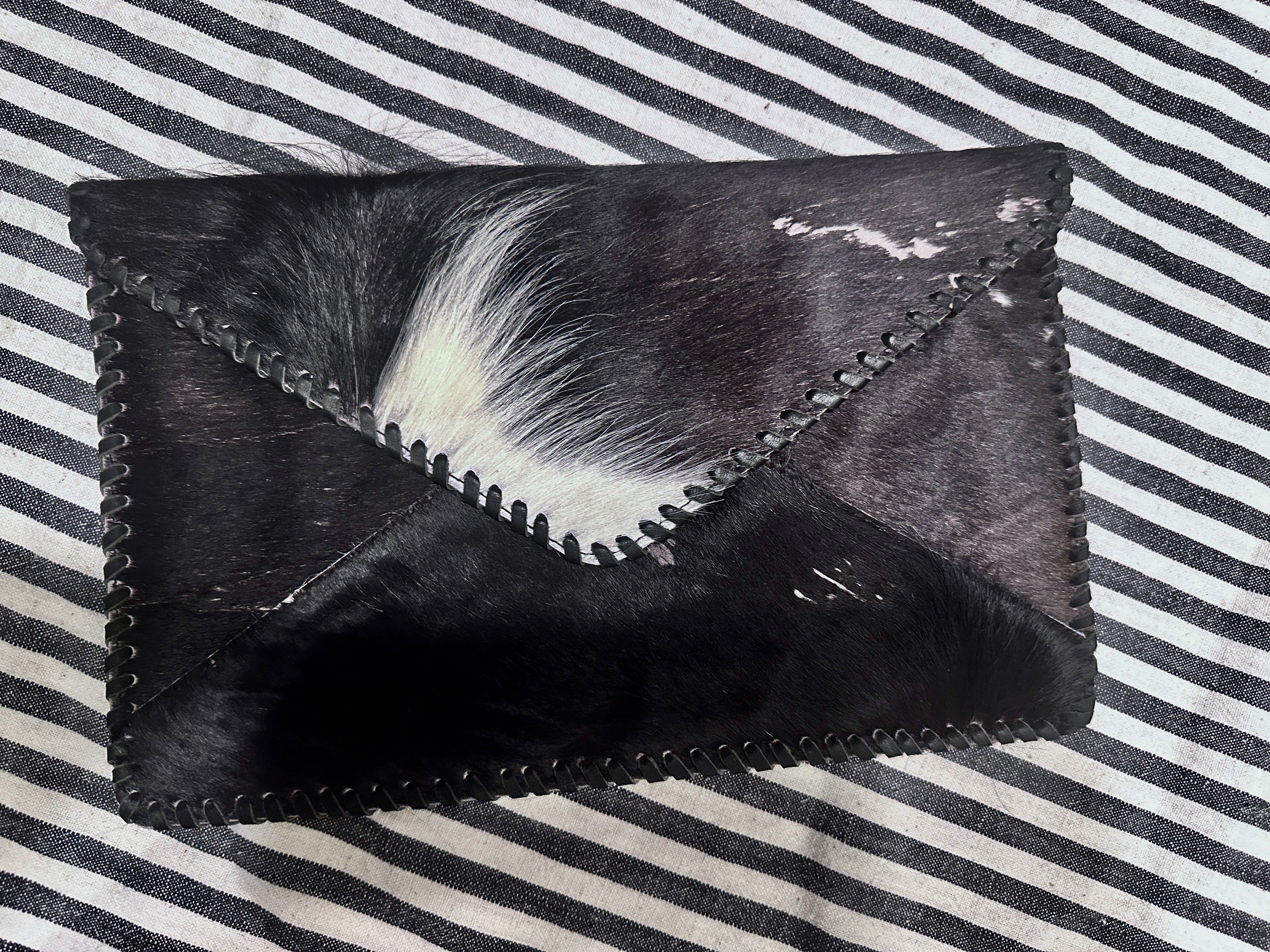 Leather Cowhide Clutch (Category: Clutches) located in Quezon City. Submitted by theessentialedit (Listing ID 1420052836, Image 1). Description: - Genuine cowhide leather - Unique black and white pattern on the front - Solid black leather back - Stitched border - Interior zipper pocket - Perfect for carrying essentials.