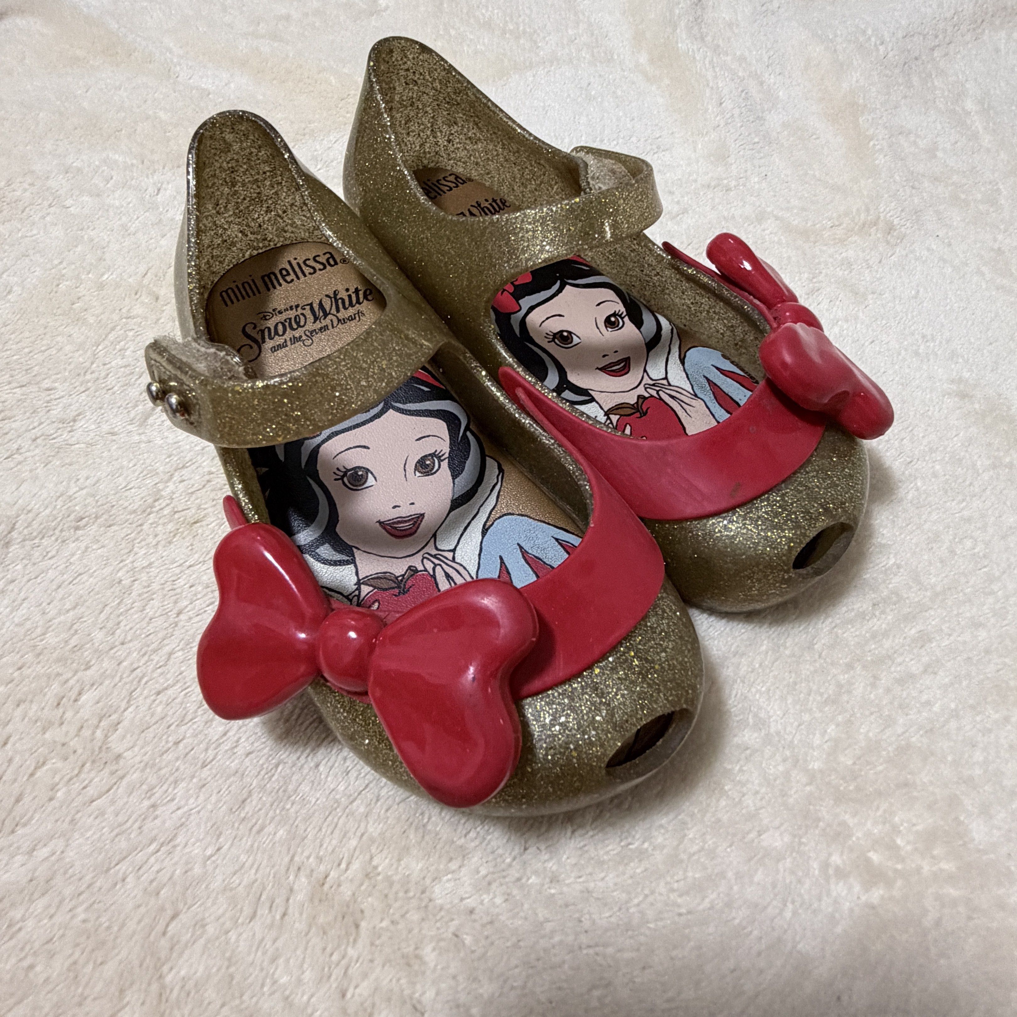 US7 Mini Melissa Snow White (Category: Babies & Kids Fashion) located in Batangas. Submitted by chloclo.declutter (Listing ID 1420013721, Image 2). Description: - Mini Melissa Snow White shoes - Gold glitter design - Red strap and bow detail - Features Snow White graphic on insole - Size: 14cm - Perfect for little Disney fans! .