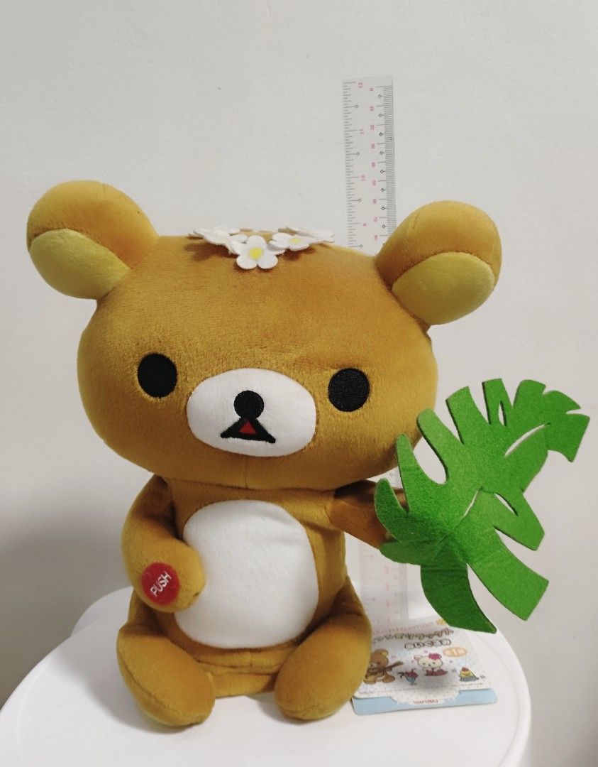Rilakkuma Battery Operated Plush Toy (Category: Plushies & Soft Toys) located in Imus. Submitted by applecheeks_05 (Listing ID 1420131343, Image 1). Description: - Adorable Rilakkuma plush toy - Features a brown bear design - Includes a white belly and flower crown - Holding a green leaf - Has a "PUSH" button on the arm - Comes with a tag - Perfect for collectors or gifting - Battery Operated - Still working.