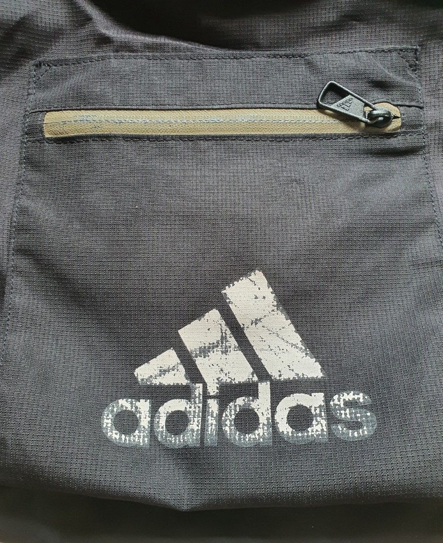 Adidas Roll-Top Backpack (Category: Backpacks) located in Meycauayan. Submitted by shoptoown (Listing ID 1420210468, Image 3). Description: Adidas roll-top backpack in black. Features a front zippered pocket and side mesh pockets. The backpack has adjustable shoulder straps and a top handle. The Adidas logo is visible on the front. The tag indicates it was made in Vietnam. Dimensions are approximately 15W x 21L..