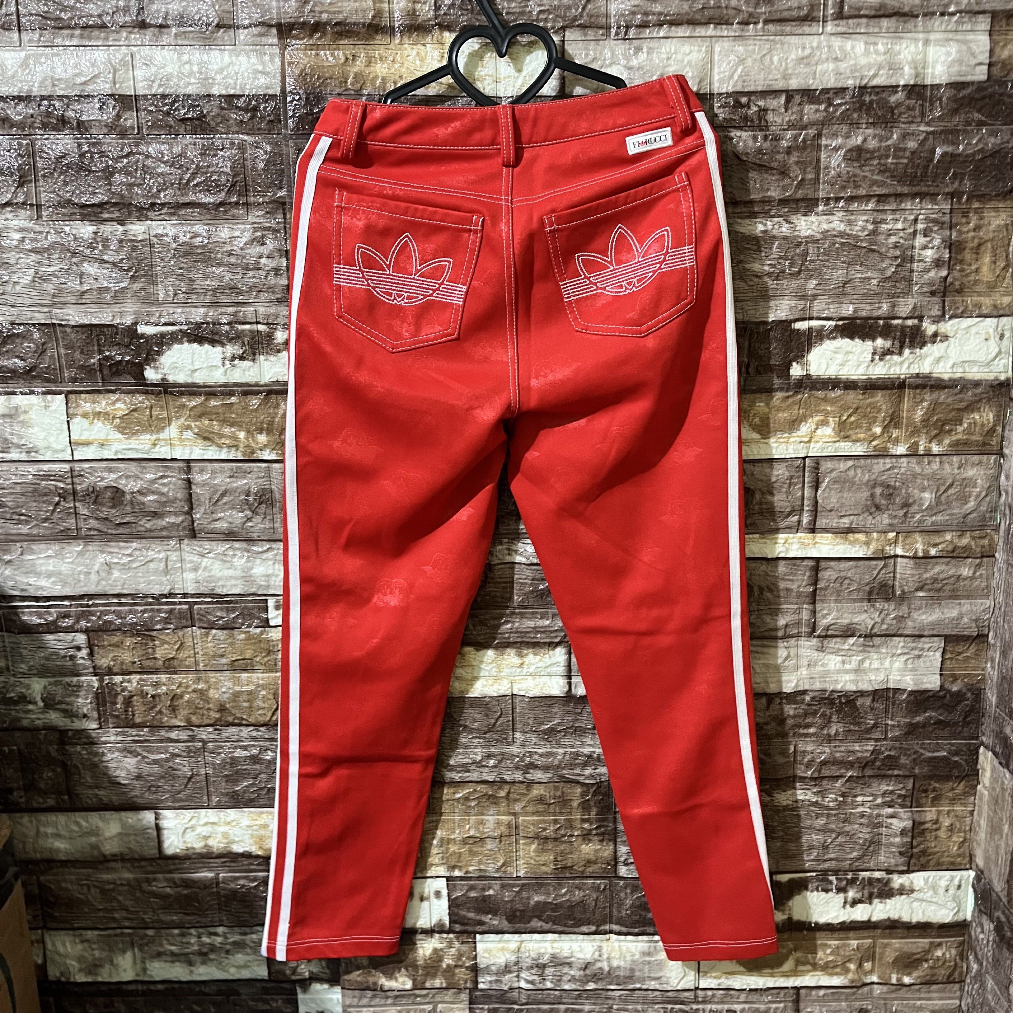 Adidas x Fiorucci Red Pants (Category: Jeans) located in Davao. Submitted by wornbycathy (Listing ID 1420325916, Image 2). Description: - Red Adidas pants - White side stripes - Fiorucci tag - Size: UK 10, US S, J S/P - Made in Vietnam - Adidas trefoil logo on back pockets - Unique fabric pattern.