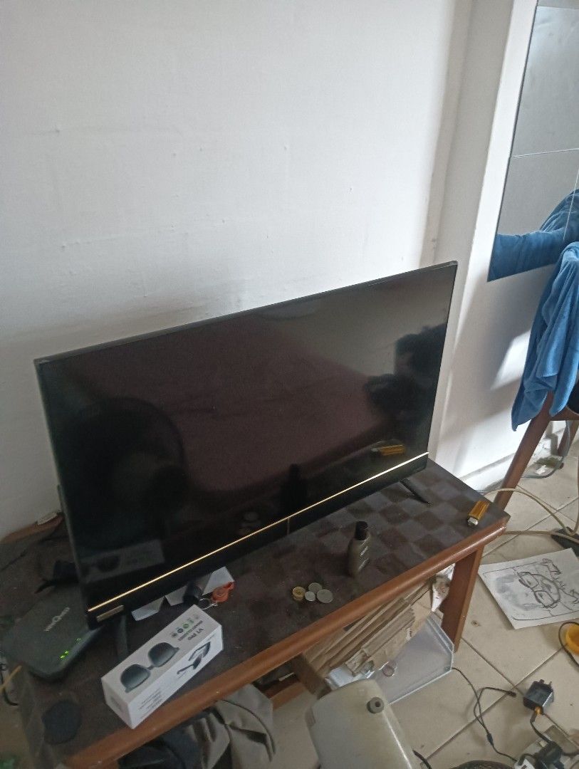 Flat Screen TV (Category: TV) located in Singapore. Submitted by baebyauau220495 (Listing ID 1420249142, Image 1). Description: - Used flat screen TV - Working condition - Black screen - Includes wooden table - Accessories on table (sunglasses, coins, bottle) not included..