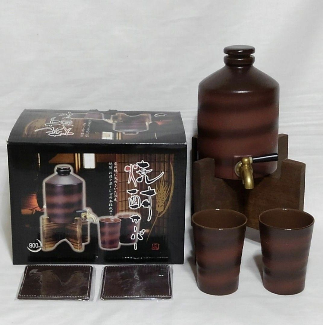 Japanese Sake Dispenser Set (Category: Coffee & Tea Tableware) located in Pangil. Submitted by kopee_matcha (Listing ID 1420298788, Image 2). Description: Japanese sake dispenser set includes a ceramic dispenser with a wooden stand, two matching cups, and two coasters. The dispenser has a tap for easy pouring. The design features a brown and black color scheme..