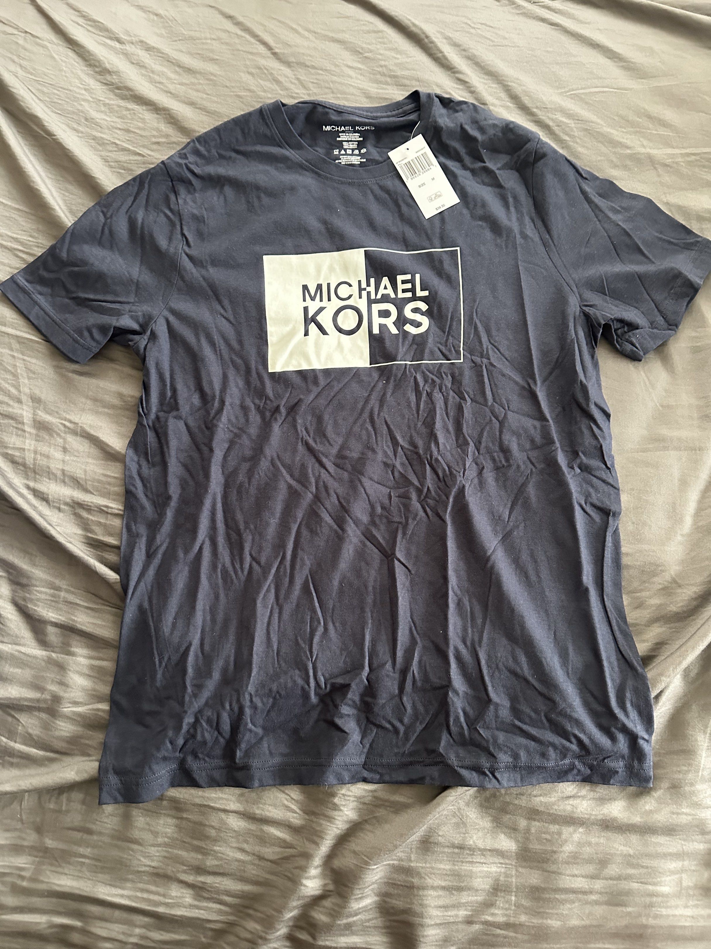 Michael Kors Navy Blue T-Shirt (Category: Tshirts & Polo Shirts ) located in Pasig City. Submitted by chiccochoco (Listing ID 1420175586, Image 1). Description: - Brand new Michael Kors t-shirt - Color: Navy blue - Features a white and black logo - Crew neck and short sleeves - Still has original tag attached - Made of soft, comfortable fabric.