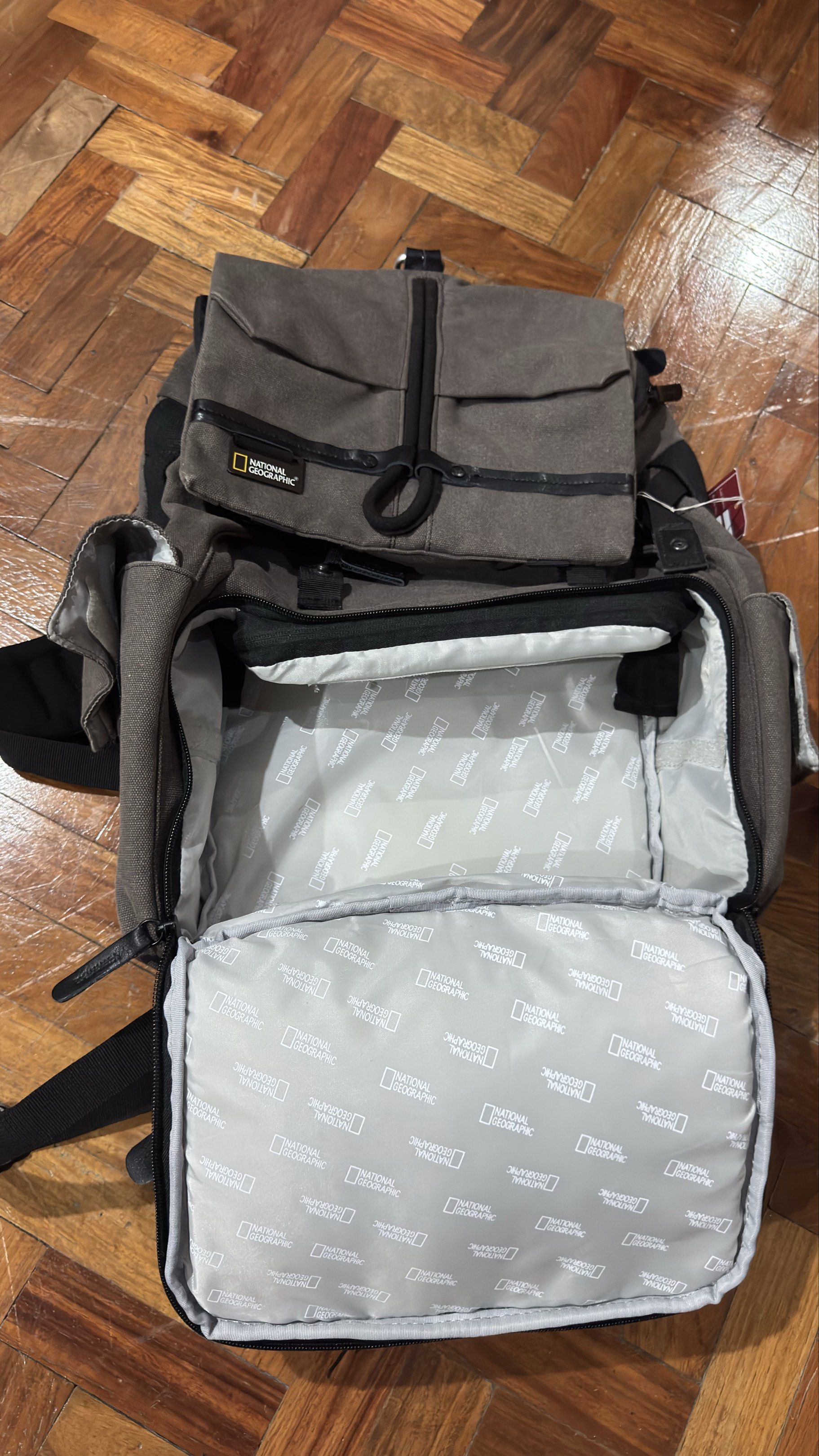 National Geographic Camera Backpack (Category: Backpacks) located in Manila. Submitted by paolo111 (Listing ID 1420299172, Image 2). Description: - National Geographic camera backpack - Gray with black accents - Multiple compartments for storage - Top flap closure - Two front pockets - Padded interior - Patterned lining - Adjustable shoulder straps -camera compartment dividers missing .