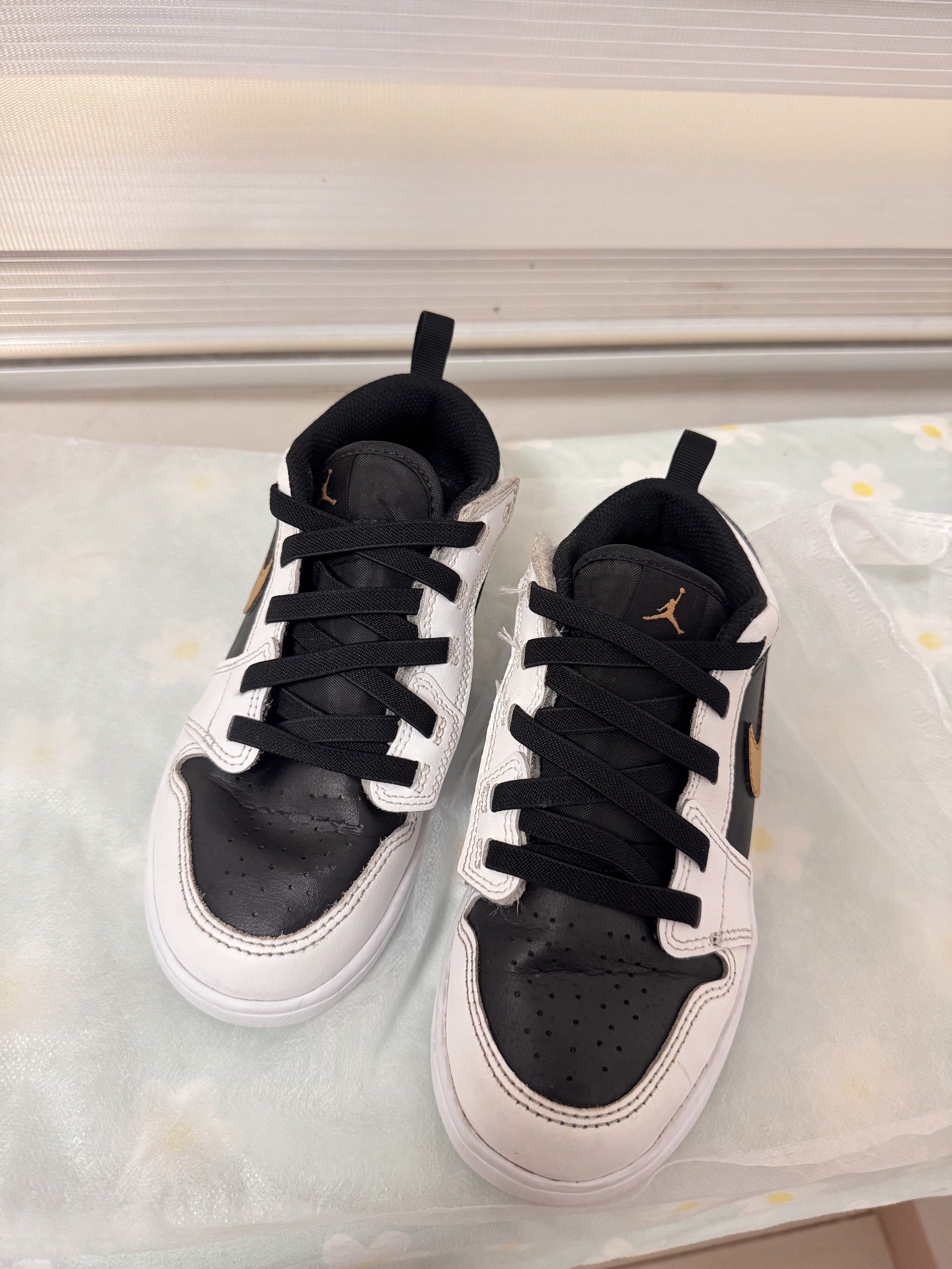 Nike Jordan 1 Low Black White Gold (Category: Sneakers) located in Silay City. Submitted by declutterwithm3 (Listing ID 1420340896, Image 3). Description: - Nike Jordan 1 Low Kids sneakers - Colorway: Black, White, Gold - Size: US 2Y / 21 cm - Low-top style - White sole - Black laces - Nike swoosh on sides - Features a pull tab for easy wear.