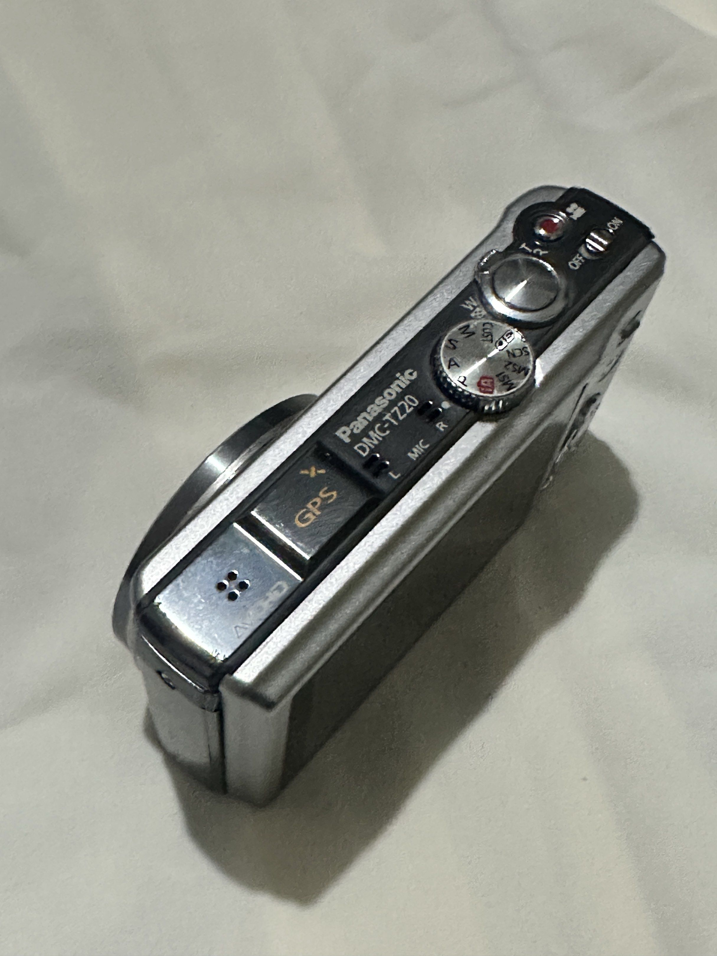 Panasonic Lumix DMC-TZ20 Digital Camera (Category: Cameras) located in Manila. Submitted by naaadaaaa (Listing ID 1420273535, Image 3). Description: Panasonic Lumix DMC-TZ20 digital camera with Leica lens. Features 16x zoom and full HD video recording. Includes GPS. The camera shows a system error related to focus. Battery and memory card slot are visible. The camera is silver in color. Zoom quality in pictures and vids are very nice!!! (Can send