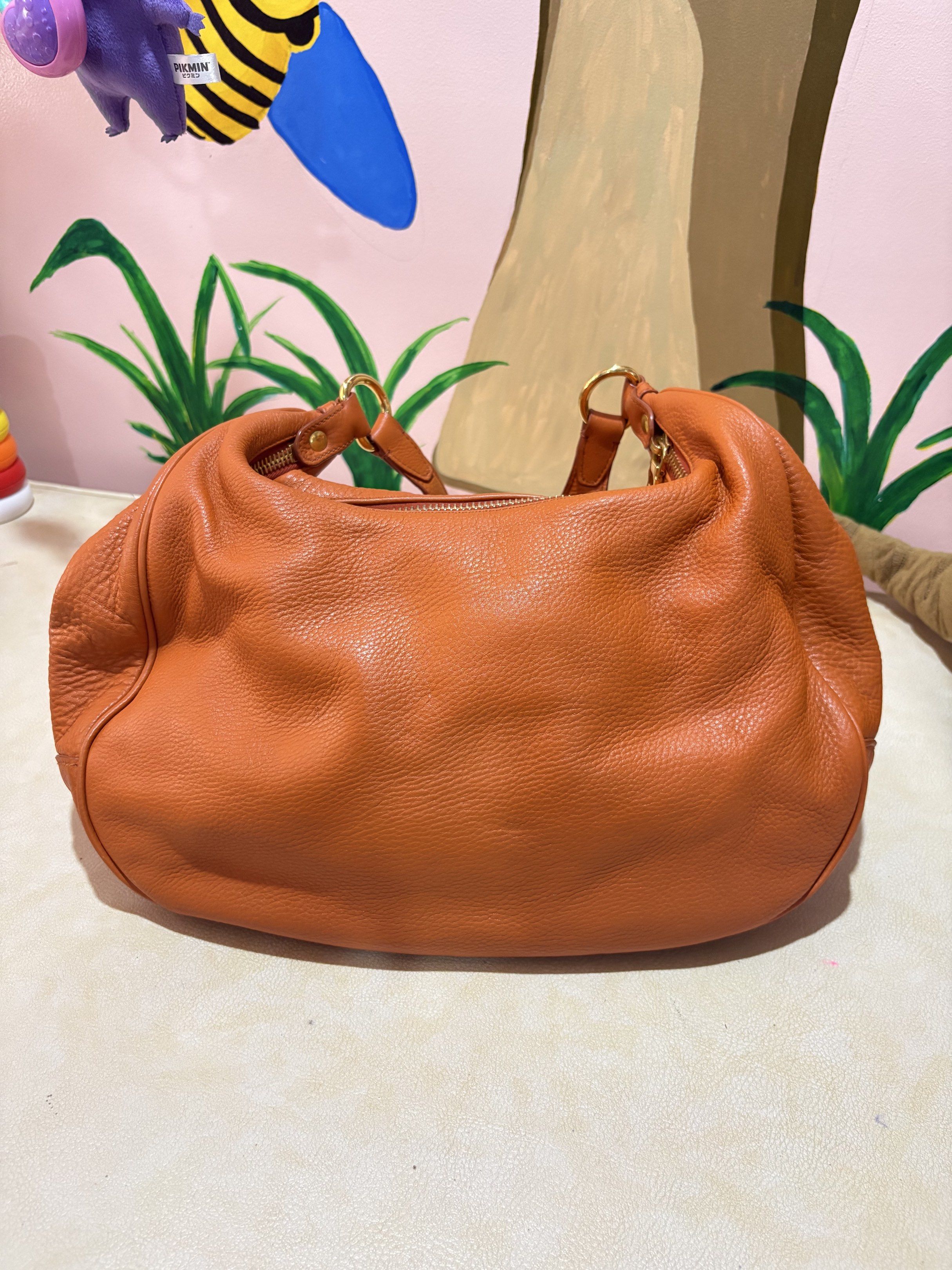 Prada Leather Hobo Bag (Category: Luxury Bags & Wallets) located in Lapu Lapu. Submitted by fashion.room05 (Listing ID 1420288856, Image 2). Description: - Authentic Prada hobo bag - Stunning orange textured leather - Secure top zipper closure - Luxurious gold-tone hardware - Comfortable leather shoulder strap - Interior zippered pocket - Prada logo plaque inside - Prada logo on the front - Fabric lining.