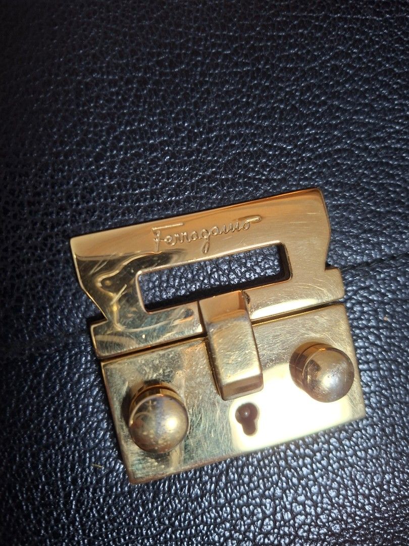 Salvatore Ferragamo Black Clutch (Category: Luxury Bags & Wallets) located in Ilagan. Submitted by dbankerscloset (Listing ID 1420305351, Image 2). Description: - Salvatore Ferragamo black clutch - Gold-tone clasp closure - Includes dust bag - Interior with multiple compartments - Features a wrist strap.