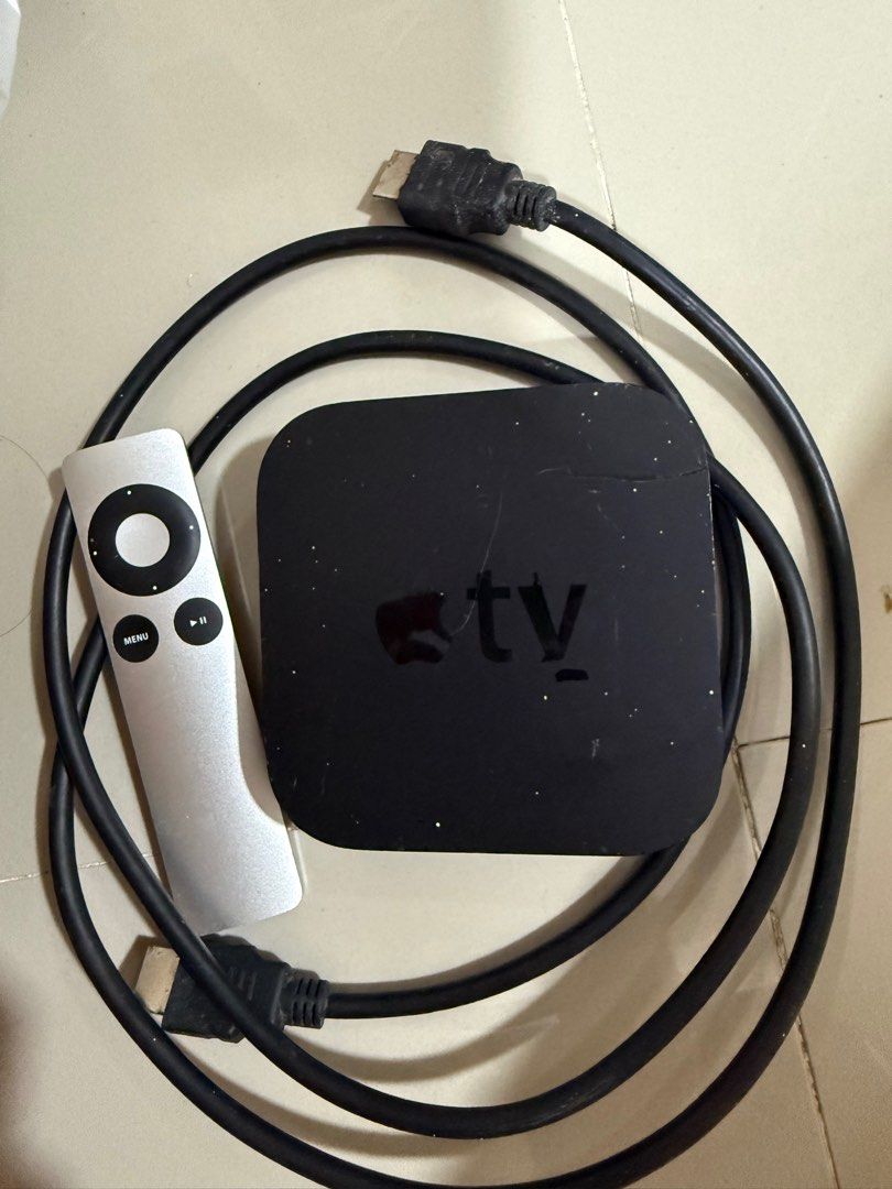 Apple TV Box with Remote and Cables (Category: TV Parts & Accessories) located in Cabuyao City. Submitted by affordable_love_items (Listing ID 1420417136, Image 1). Description: - Apple TV box included - Comes with remote control, power cable, and HDMI cable - Ports: HDMI, Ethernet, Optical Audio - Features a menu button and navigation controls on the remote - Apple logo visible - Device is in good working condition.