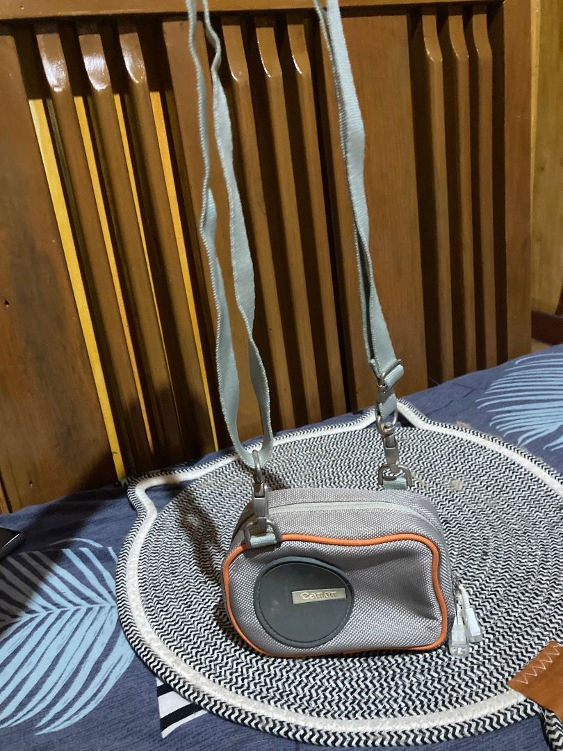 Canon Camera Bag with Strap (Category: Camera Bags & Carriers) located in La Trinidad. Submitted by clawver123 (Listing ID 1420489815, Image 3). Description: - Canon camera bag for protection - Gray exterior with orange trim - Features the Canon logo - Detachable shoulder strap included - Black fabric interior - Secure zippered closure.
