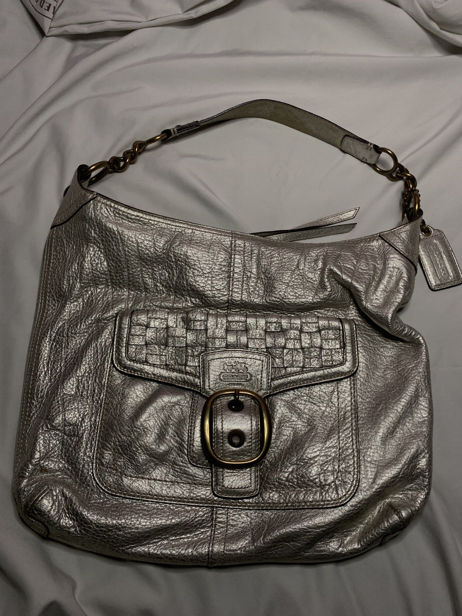 Coach Silver Hobo Handbag (Category: Luxury Bags & Wallets) located in Quezon City. Submitted by jjiel (Listing ID 1420449521, Image 1). Description: - Silver Coach hobo handbag - Woven front pocket - Buckle closure - Shoulder strap with chain detail - Coach hangtag included - Coach pattern lining - Silver metallic finish.