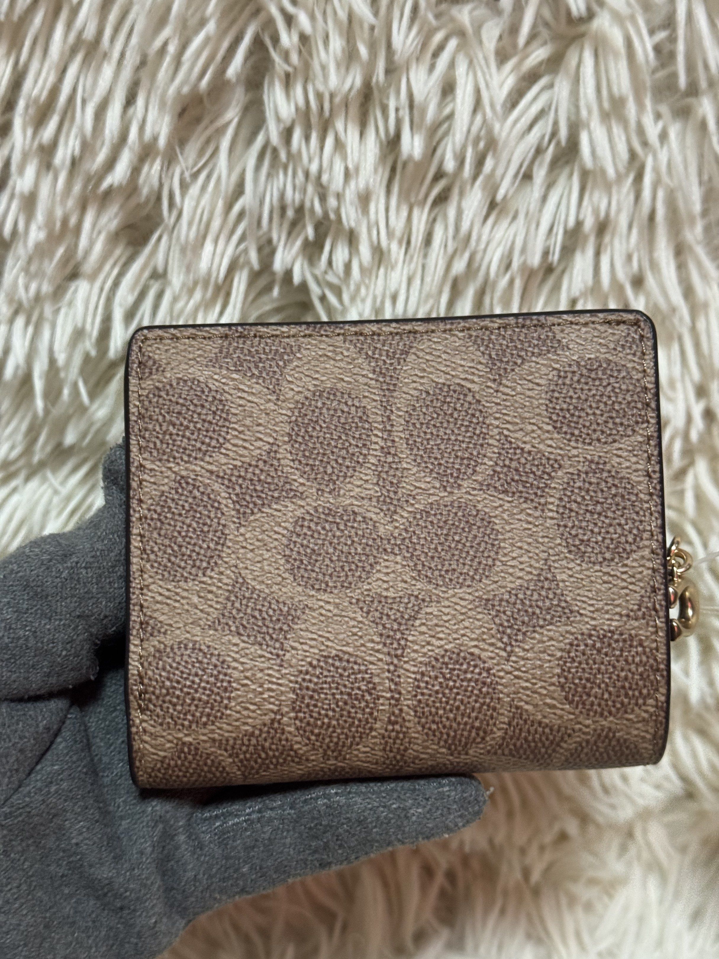 Coach Snap Wallet in Signature Canvas (Category: Luxury Bags & Wallets) located in Rodriguez. Submitted by nancyb13 (Listing ID 1420501139, Image 2). Description: Coach snap wallet features the signature canvas pattern in brown. It has multiple card slots, a clear ID window, and a zippered coin compartment. The wallet includes a Coach hang tag and a gold-tone zipper. The comparable value is $178.00 USD / $220.00 CAD..