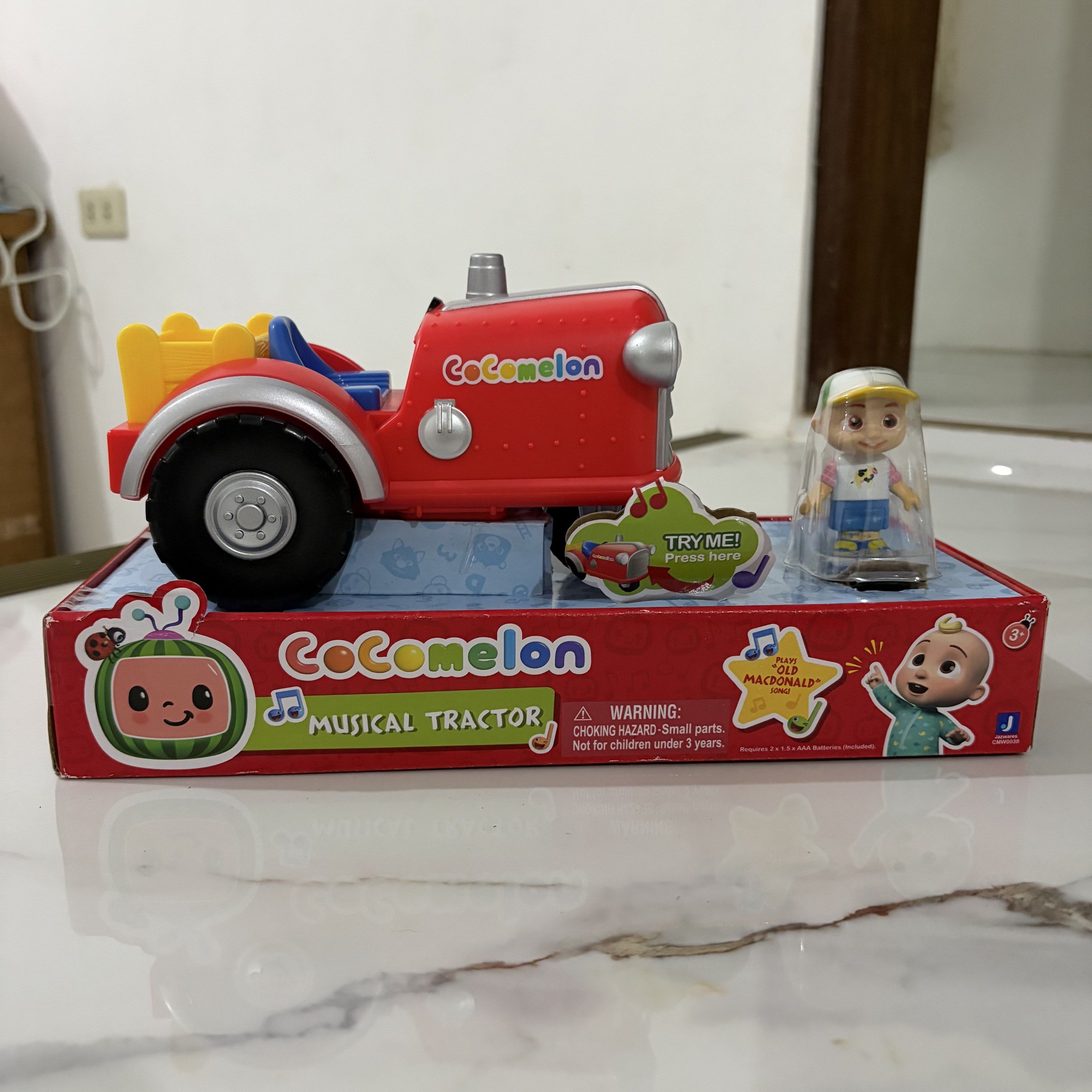 CoComelon Musical Tractor Toy (Category: Kids Toys) located in Bulacan. Submitted by speczone (Listing ID 1420497446, Image 2). Description: - CoComelon Musical Tractor toy included. - Comes with a figure. - Tractor color: Red with black wheels and yellow bed. - Features the 'Try Me! Press here' button. - Box features the CoComelon logo and 'Musical Tractor' text. - from US box (padala from a relative).
