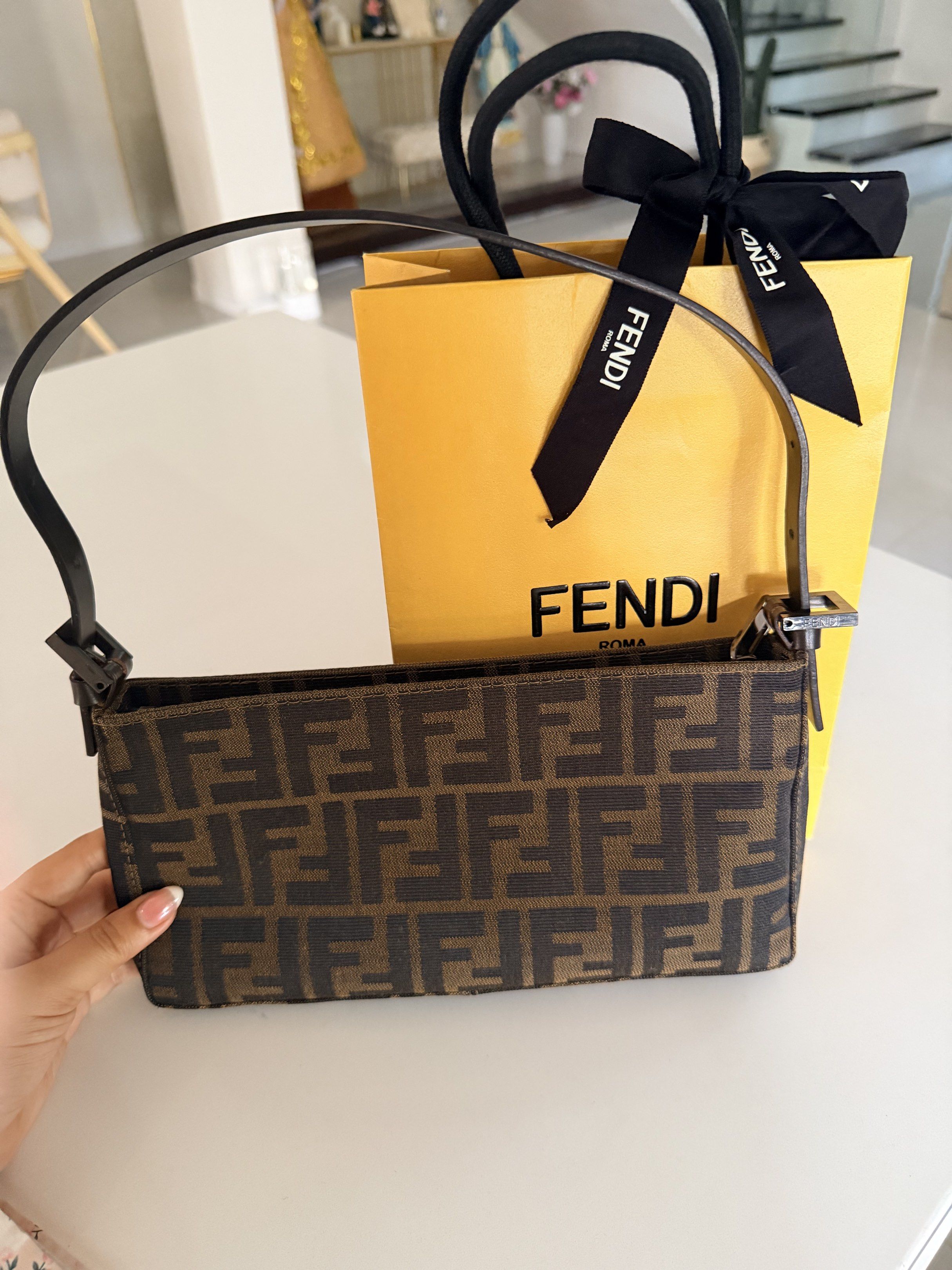 Fendi Baguette Bag (Category: Luxury Bags & Wallets) located in Apalit. Submitted by lunakobe (Listing ID 1420422626, Image 3). Description: - Authentic Fendi Baguette bag - Features the iconic FF logo pattern - Comes with Fendi shopping bag and ribbon - Brown leather strap - Silver hardware - A stylish and classic accessory.
