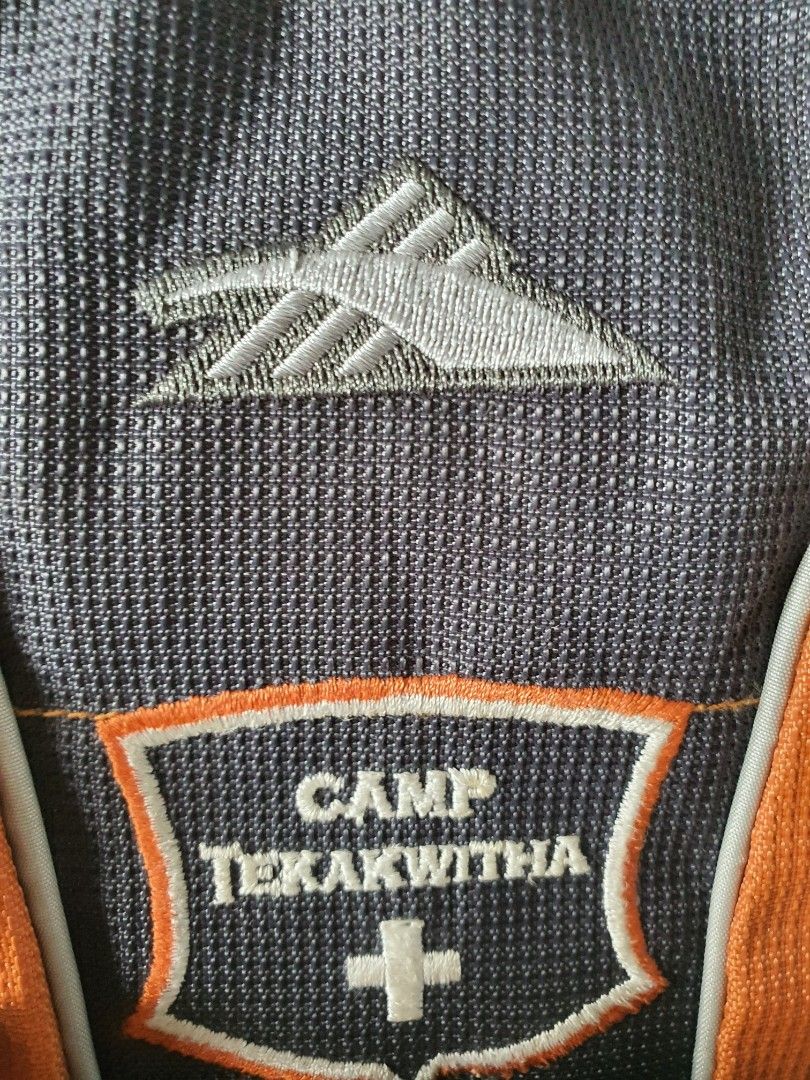 High Sierra Camp Tekakwitha Hydration Backpack (Category: Backpacks) located in Meycauayan. Submitted by shoptoown (Listing ID 1420365173, Image 3). Description: - Orange and gray hydration backpack - Features the "Camp Tekakwitha" logo - Multiple compartments for storage - Adjustable straps for a comfortable fit - Breathable mesh back panel - High Sierra branded clips and zipper pulls - Designed for outdoor activities.