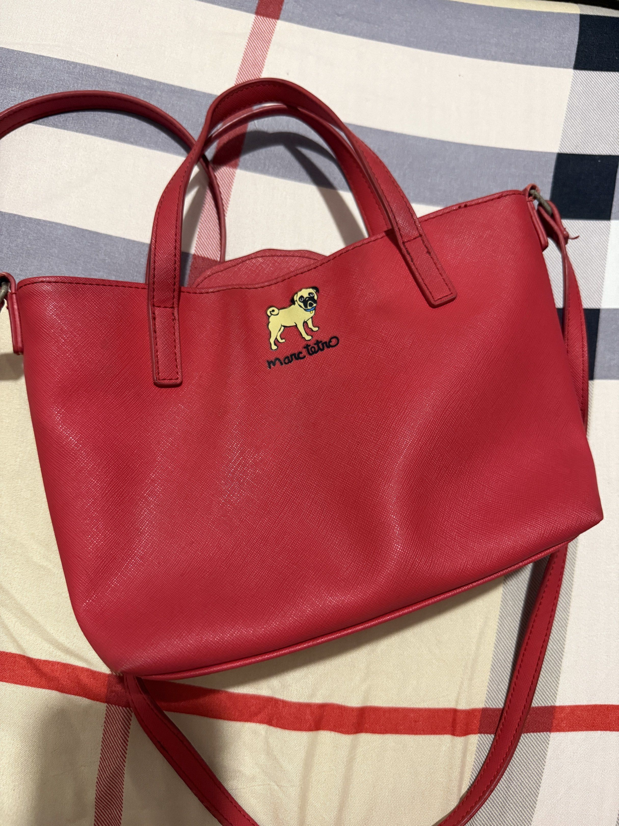 Marc Tetro Pug Handbag (Category: Luxury Bags & Wallets) located in Mandaluyong City. Submitted by itsashleyj48153 (Listing ID 1420484310, Image 2). Description: - Red handbag with a pug design by Marc Tetro - Includes top handle and detachable shoulder strap - Interior lined with black and white stripes - Visible stains on the inside - Few scratches on the dog (last pic) - Hardware: a little rusty.