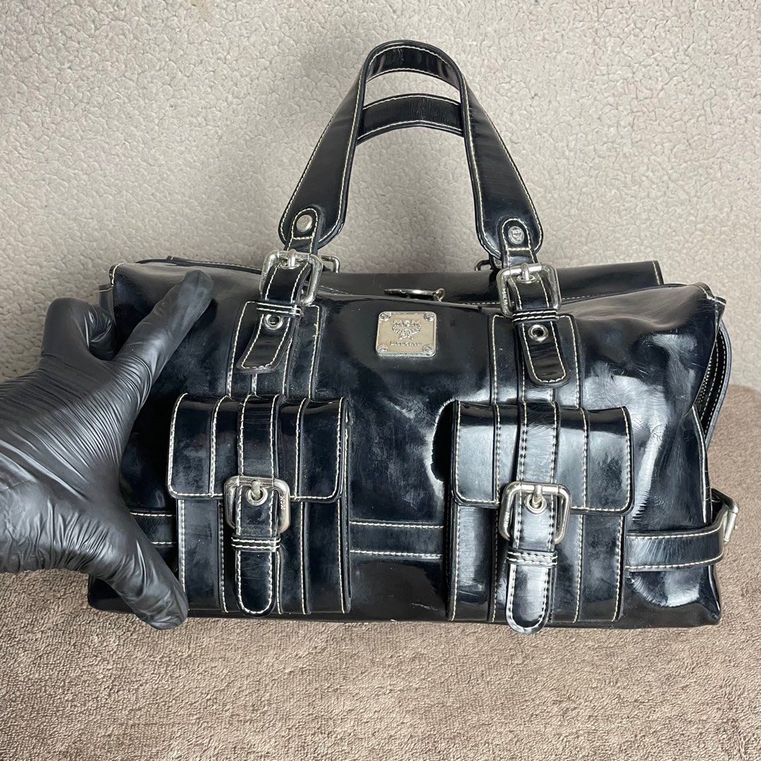 MCM Black Patent Leather Handbag (Category: Luxury Bags & Wallets) located in Angeles City. Submitted by tinderolitthrift.ph (Listing ID 1420546510, Image 3). Description: - MCM black patent leather handbag - Patent leather finish - Two front pockets with buckles - Top handles - Zip closure - Patterned lining - Interior zip pocket - MCM logo details - Silver-tone hardware - White stitching.
