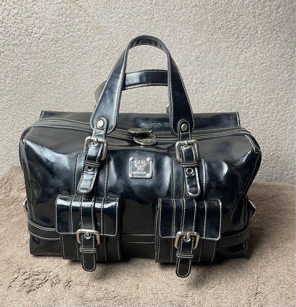 MCM Black Patent Leather Handbag (Category: Luxury Bags & Wallets) located in Angeles City. Submitted by tinderolitthrift.ph (Listing ID 1420546510, Image 1). Description: - MCM black patent leather handbag - Patent leather finish - Two front pockets with buckles - Top handles - Zip closure - Patterned lining - Interior zip pocket - MCM logo details - Silver-tone hardware - White stitching.