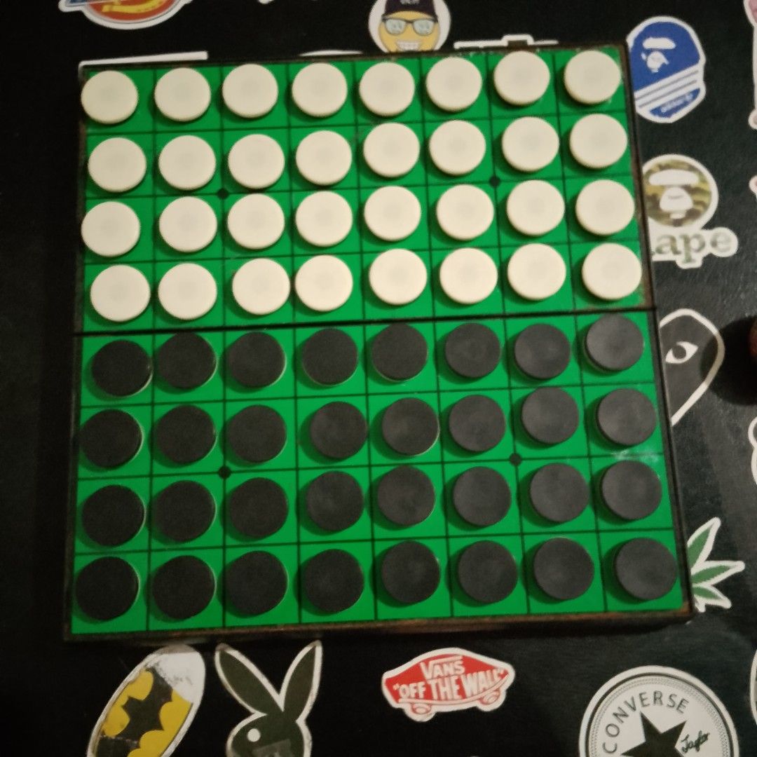 Othello Magnetic Board Game (Category: Board Games & Puzzles) located in Calumpit. Submitted by BCHThriftShop (Listing ID 1420538396, Image 1). Description: Othello board game includes the game board, black and white game pieces, and storage containers. The board is green with a grid pattern. The game pieces are black and white discs. The game is complete with all the necessary components for play. The game board folds in half for easy storage..
