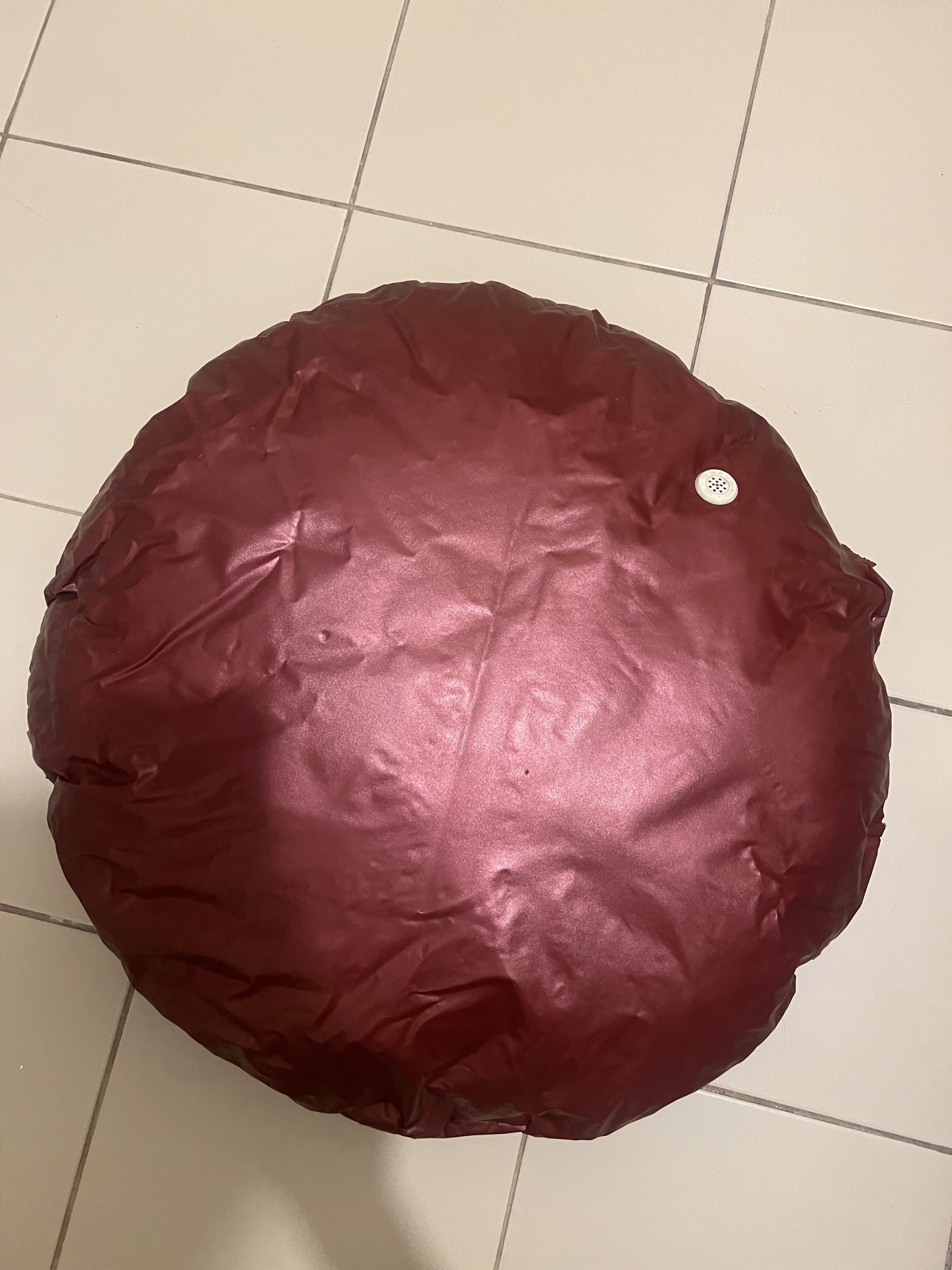 Round Maroon Bean Bag (Category: Cushions & Throws) located in Cainta. Submitted by barbie714 (Listing ID 1420513901, Image 2). Description: - Maroon pillow with a shiny, metallic finish. - Circular shape. - Minor tear on the side, exposing filling..
