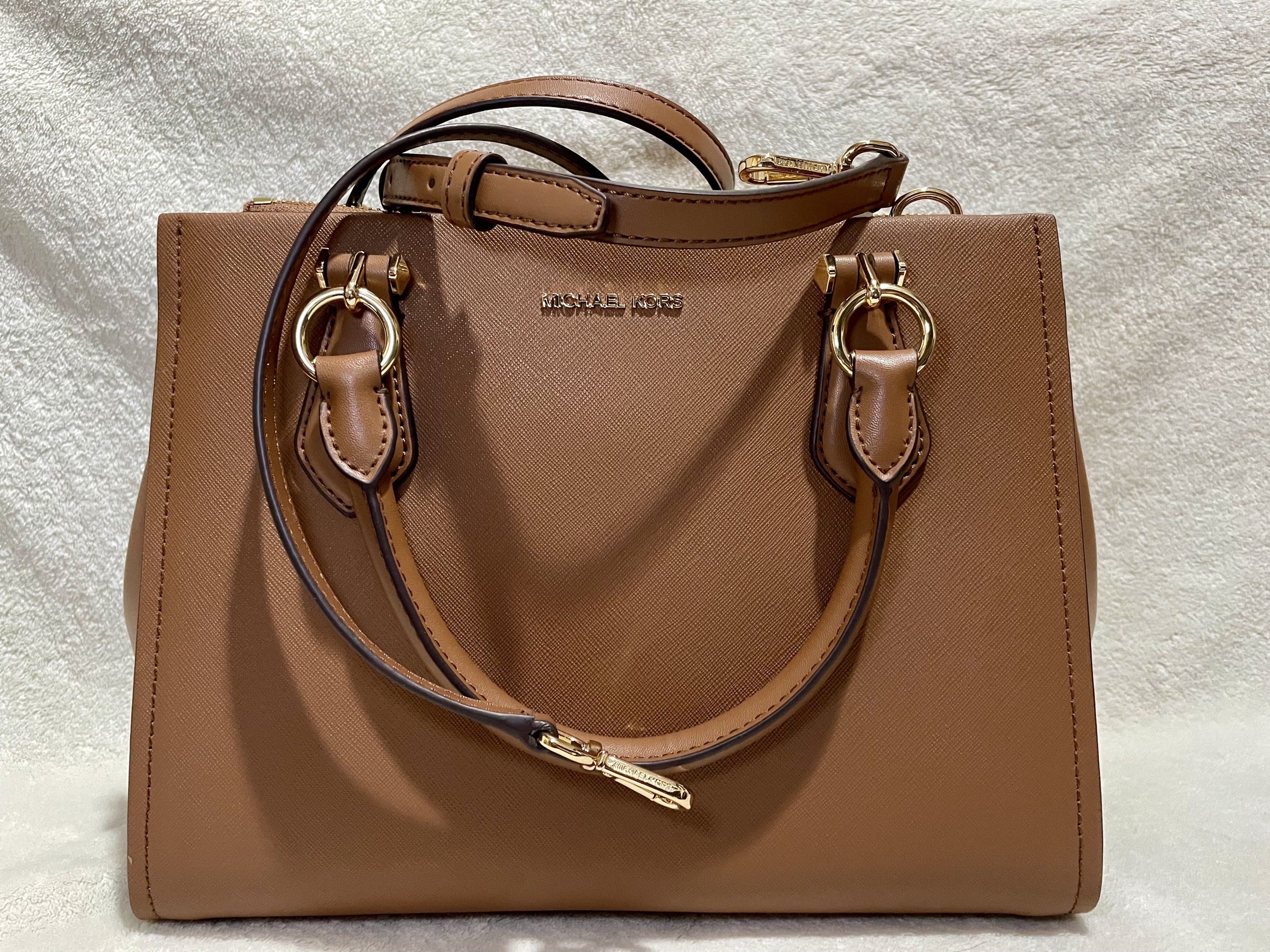 Michael Kors Marilyn Saffiano Satchel Bag (Category: Luxury Bags & Wallets) located in Mandaluyong City. Submitted by wysluxe (Listing ID 1420607236, Image 2). Description: - Original Michael Kors satchel bag - Brown exterior with gold-tone hardware - Top handle and detachable shoulder strap - Zip closure - Lined interior - Includes card - Michael Kors logo visible - 30x21x13cm.