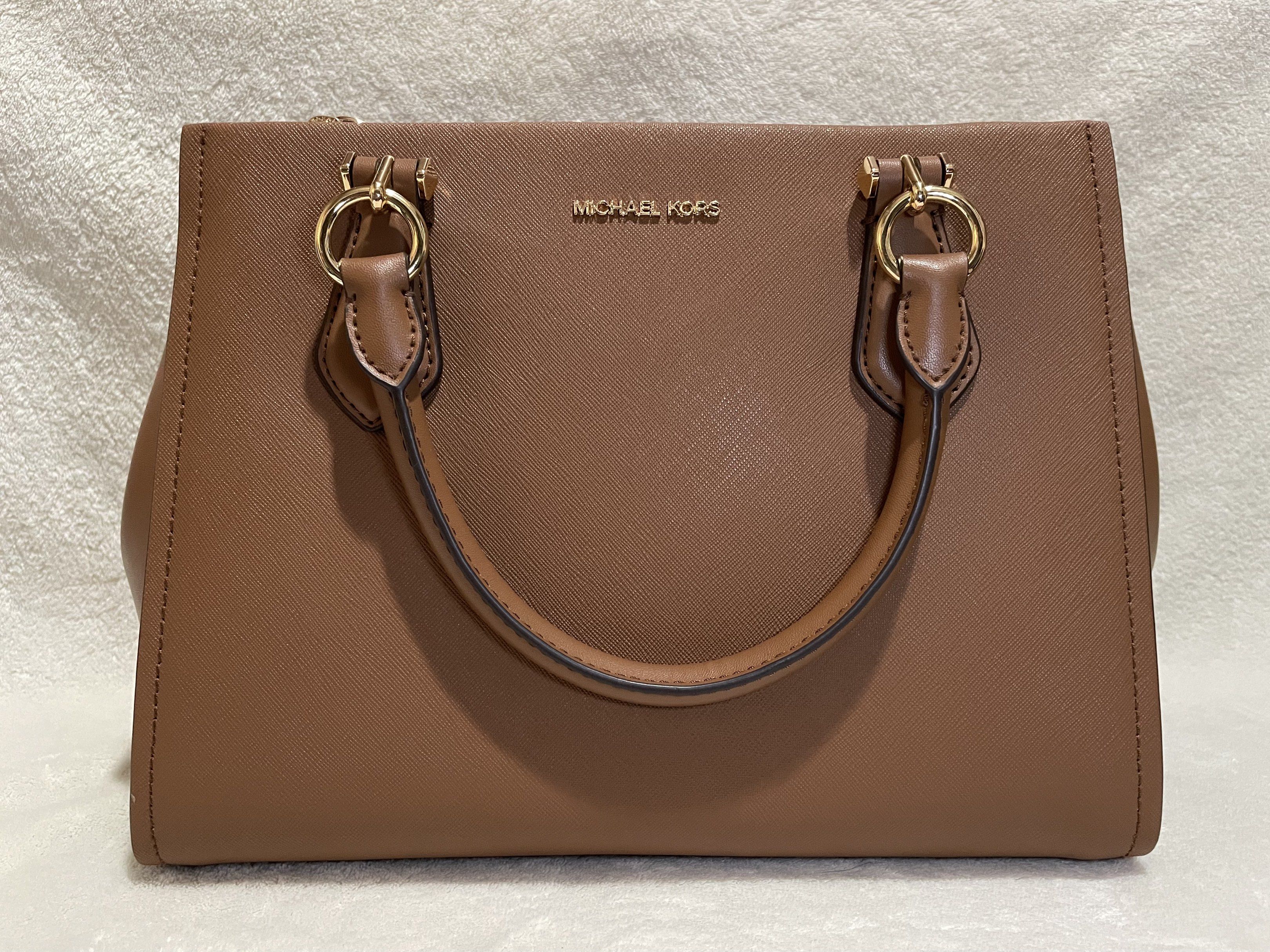 Michael Kors Marilyn Saffiano Satchel Bag (Category: Luxury Bags & Wallets) located in Mandaluyong City. Submitted by wysluxe (Listing ID 1420607236, Image 3). Description: - Original Michael Kors satchel bag - Brown exterior with gold-tone hardware - Top handle and detachable shoulder strap - Zip closure - Lined interior - Includes card - Michael Kors logo visible - 30x21x13cm.