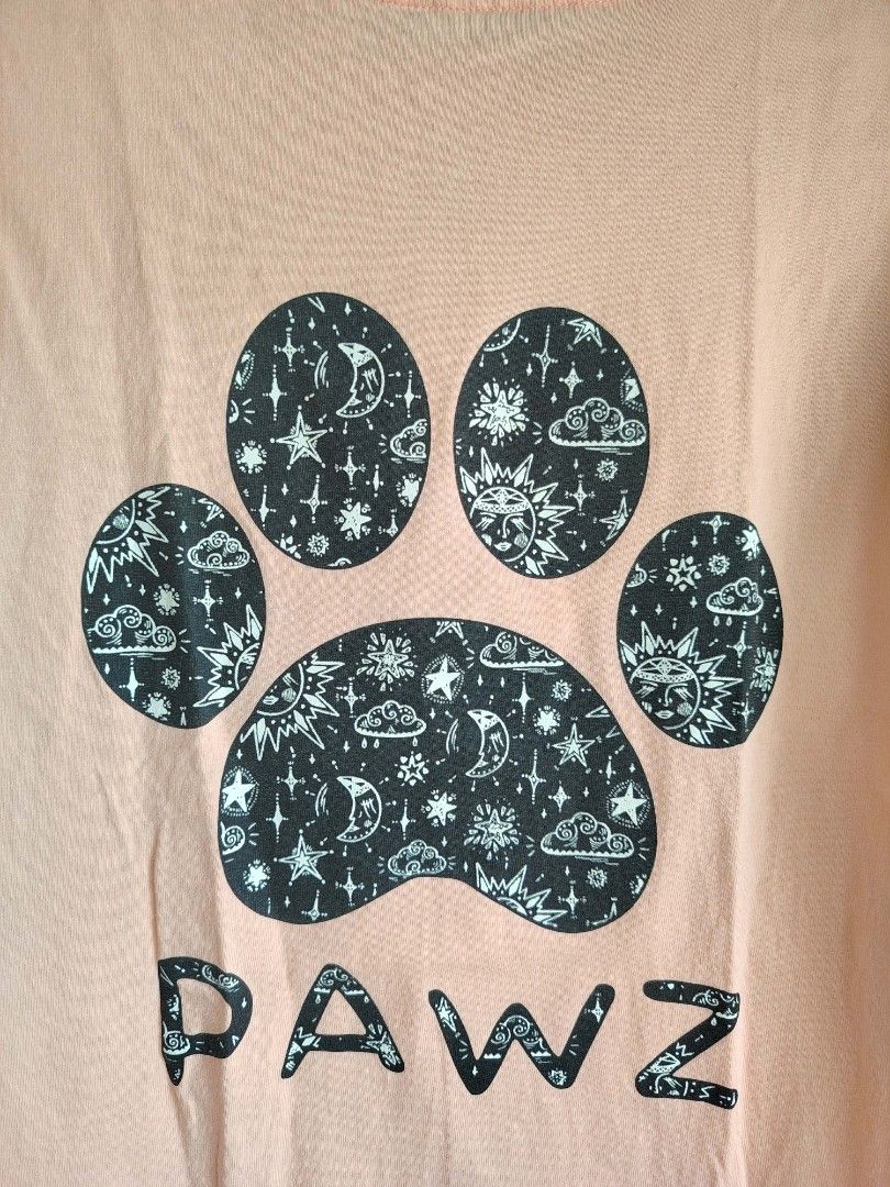 PAWZ Graphic T-Shirt (Category: Tshirts & Polo Shirts ) located in Pasay City. Submitted by ceeeeee (Listing ID 1420621631, Image 3). Description: - Peach-colored t-shirt - Paw print design - Space-themed pattern on the back - Small paw print logo on the front - "PAWZ" printed below the logo - Short sleeves - Crew neck.