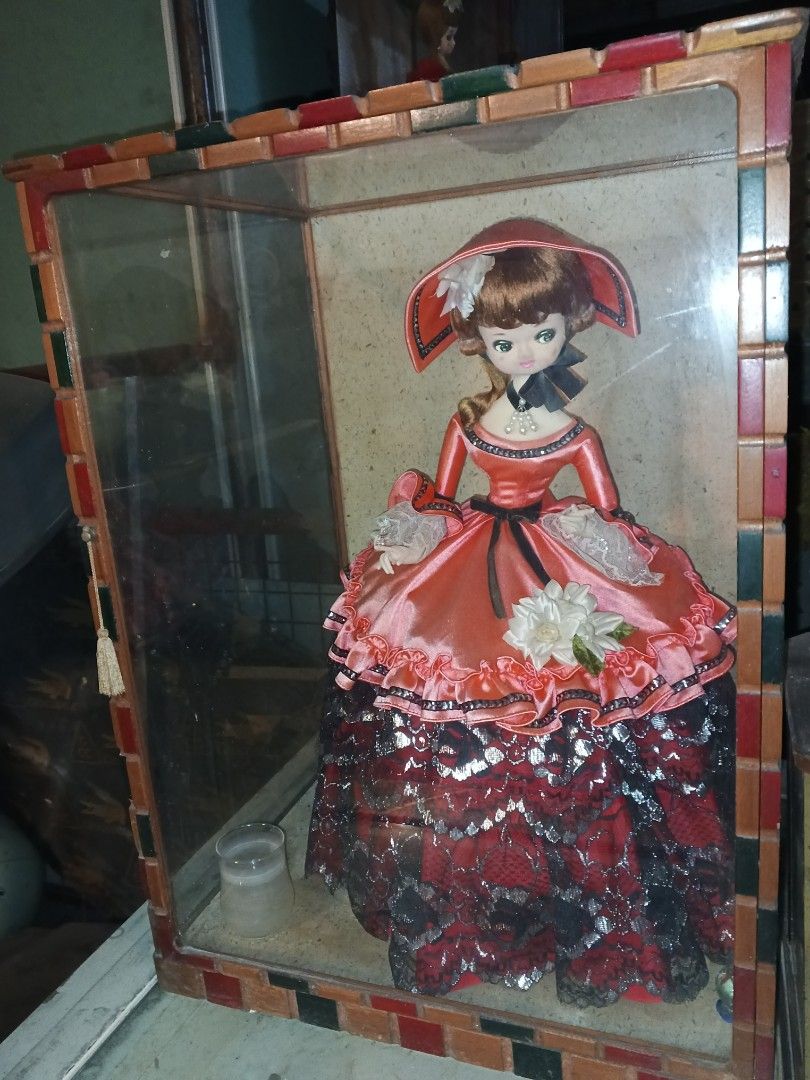Big Vintage Doll in Display Case (Category: Vintage Collectibles) located in Caloocan City. Submitted by gemmareas571129 (Listing ID 1420741221, Image 1). Description: - Vintage doll in decorative display case - Doll is wearing a red and black dress and hat - Display case features a colorful tiled frame - Includes a small candle holder.