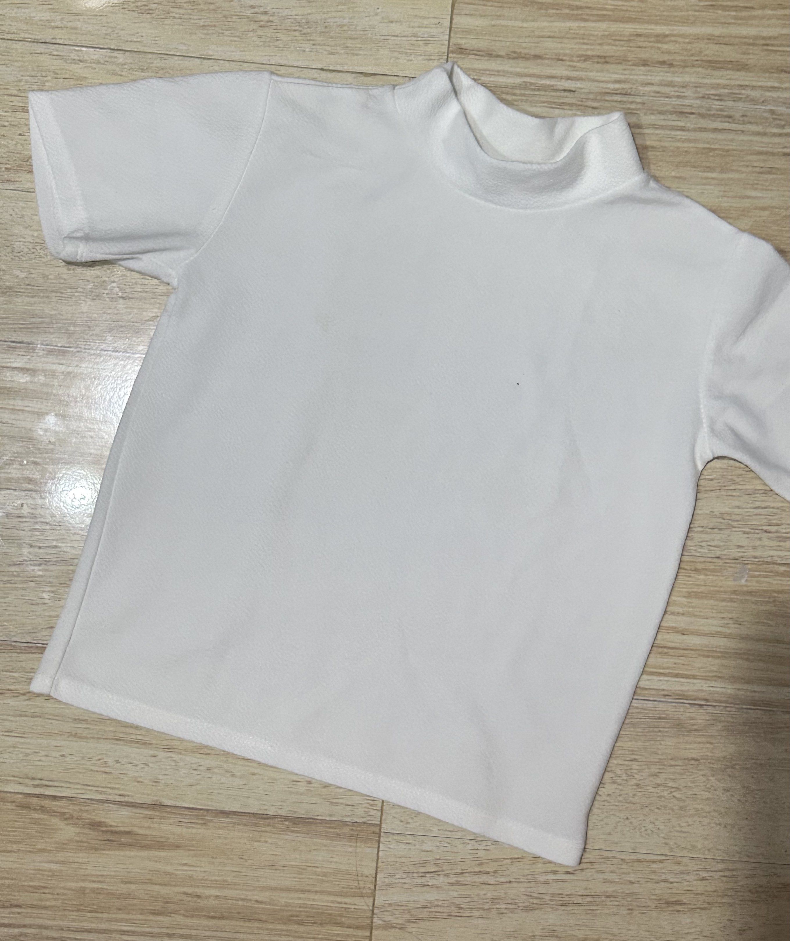 White Turtleneck Short Sleeve Shirt (Category: Shirts) located in Dagupan City. Submitted by suarteph (Listing ID 1420736920, Image 1). Description: - White short-sleeved shirt - Turtleneck collar - Textured fabric - Solid white color - Small stain present -not stretchable.