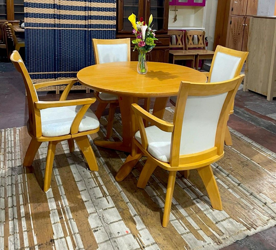 Wooden Round Dining Table with Swivel Chairs (Category: Tables & Sets) located in Quezon City. Submitted by kimmy026 (Listing ID 1420618256, Image 2). Description: Dining set includes a round wooden table and four swivel chairs. The table has a light wood finish and a unique base design. The chairs have white cushioned seats and backs. Table dimensions: H-28, D-41.5 inches. Swivel chair dimensions: H-17/35, L-21.5, W-17.5 inches..