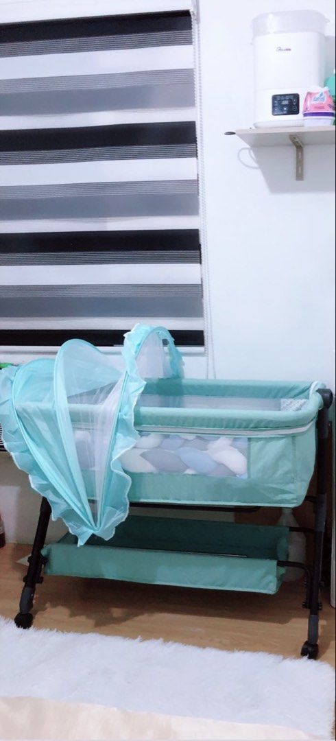 Baby Crib with Mosquito Net (Category: Cots & Cribs) located in Cavite. Submitted by butfirstdecluttering (Listing ID 1424157683, Image 2). Description: - Baby crib with mosquito net - Teal frame - Includes a storage shelf - Light-colored interior with patterned design - Minor knitting stain on fabric Issue my knting stain di msydo kta pero natatanggl nmn at my bakbak sa tela ntatamaan ksi ng upuan pero ok na ok pa di msyado ngmt ni baby .