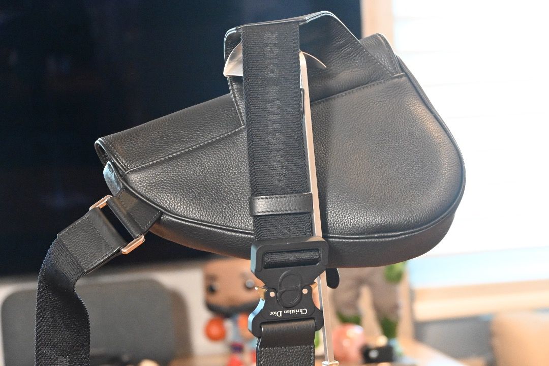 Christian Dior Saddle Bag Black - Men's (Category: Luxury Bags & Wallets) located in Muntinlupa City. Submitted by honestlygood (Listing ID 1423982570, Image 2). Description: Black leather saddle bag from Christian Dior. Features an adjustable strap with a metal buckle closure. The bag has a curved shape with a flap closure. The strap has the Christian Dior logo..