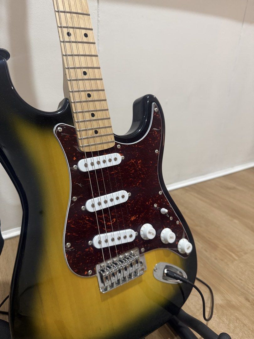 Electric Guitar with Amplifier and Accessories (Stratocaster) (Category: Musical Instruments) located in Manila. Submitted by archivesbyelle (Listing ID 1424152286, Image 2). Description: - Electric guitar with sunburst finish, maple fretboard, and tortoise pick guard (still has plastic on it) - RJ guitar amplifier (15 watts) - Inclusions: 2 guitar picks, strap, cable, tremolo arm, and allen wrench/keys, capo, Rixton guitar stand, Rixton guitar t